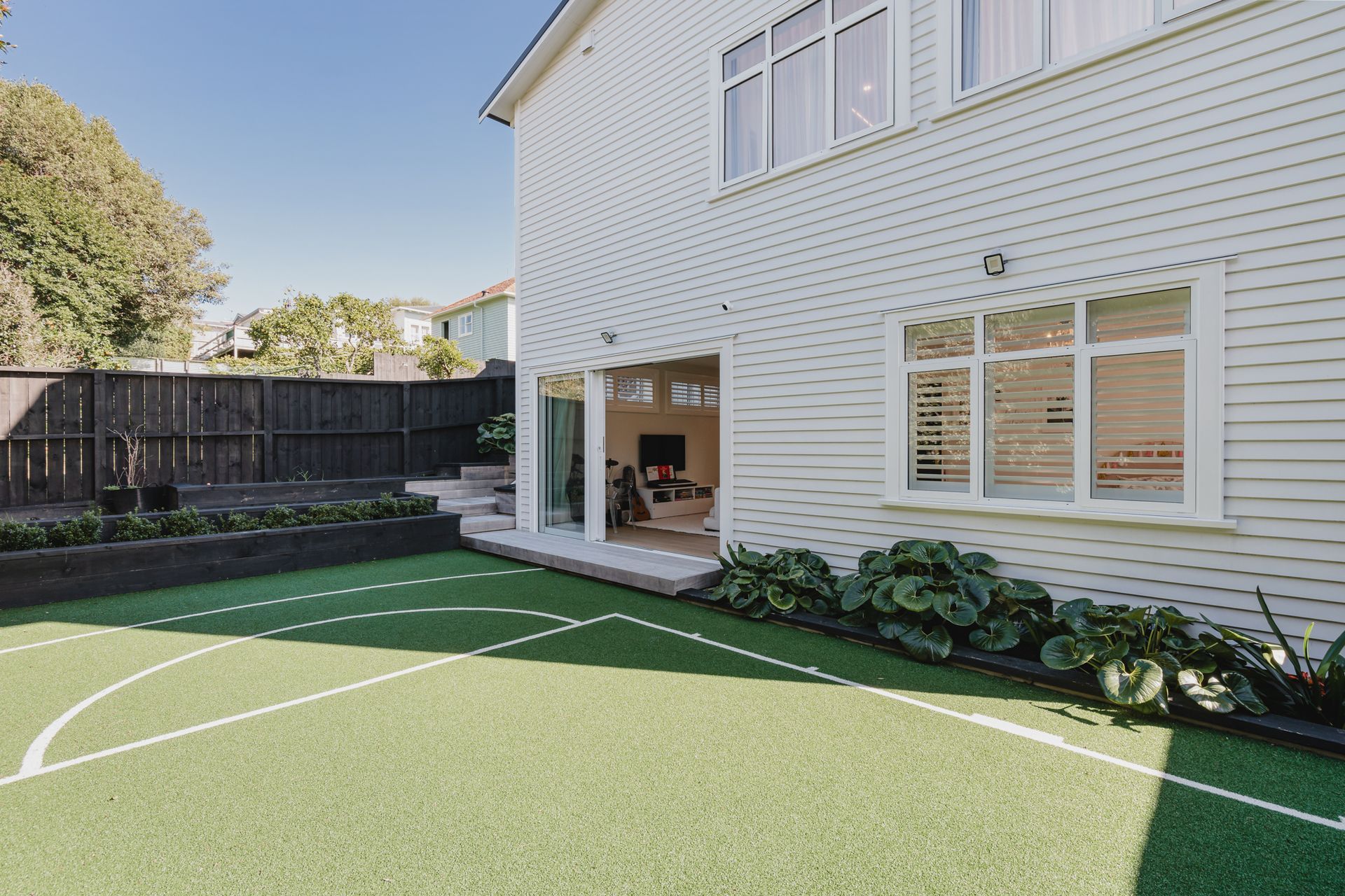 Westmere Bungalow | New-Build Residence | External view of rear sports court extending from the lower childrens wing.