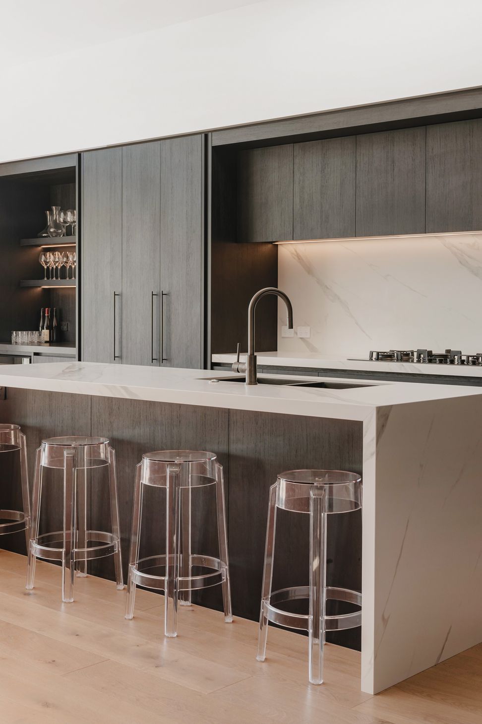 Westmere Bungalow | New-Build Residence | Internal view of bespoke dark wood kitchen with waterfall edge marble island and splash back.