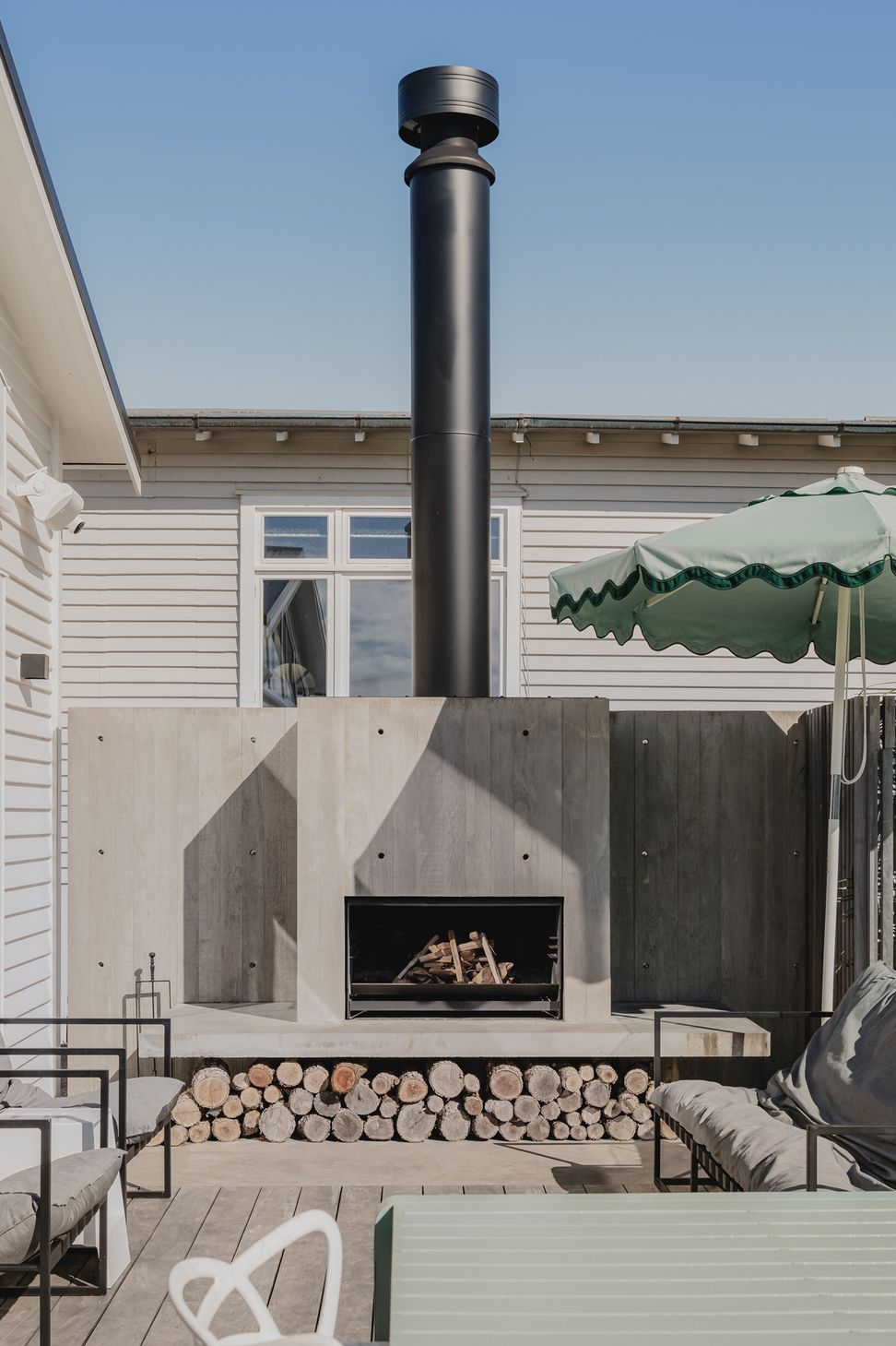 Westmere Bungalow | New-Build Residence | External view of in situ concrete wood burning fireplace sitting next to the salt water pool in the outdoor entertainment area.