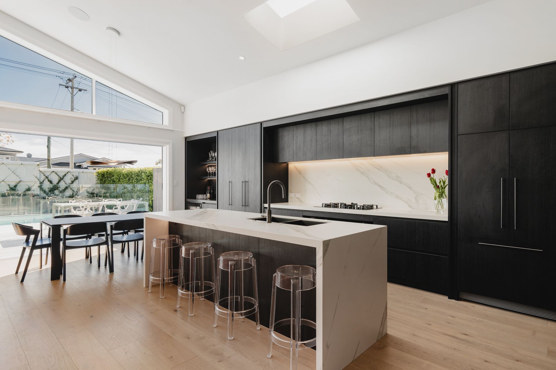 Westmere Bungalow | New-Build Residence | Internal View of open plan living, kitchen and dining area, with high pitch vaulted ceilings, large bifold doors, carefully places skylight and bespoke darkwood kitchen.