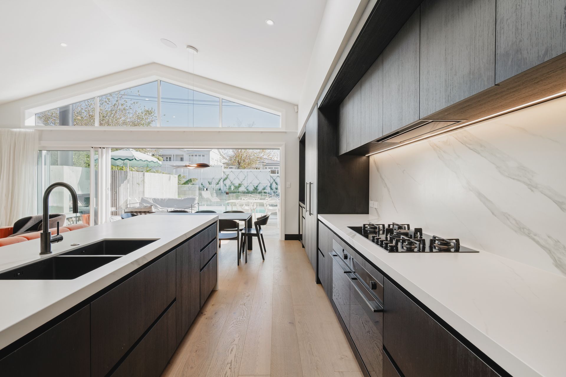 Westmere Bungalow | New-Build Residence | Internal view of bespoke dark wood kitchen with marble island and splash back.