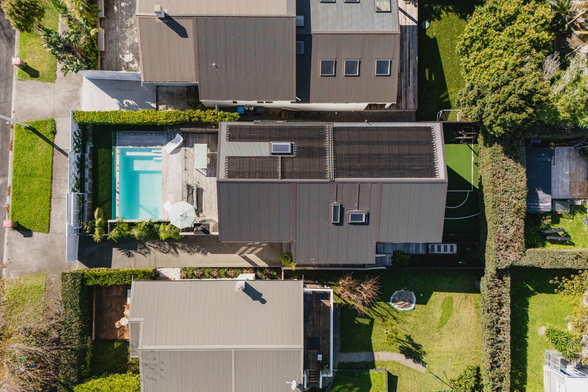 Westmere Bungalow | New-Build Residence | Aerial view from swimming pool and outdoor fireplace in the front to the sports court in the back.