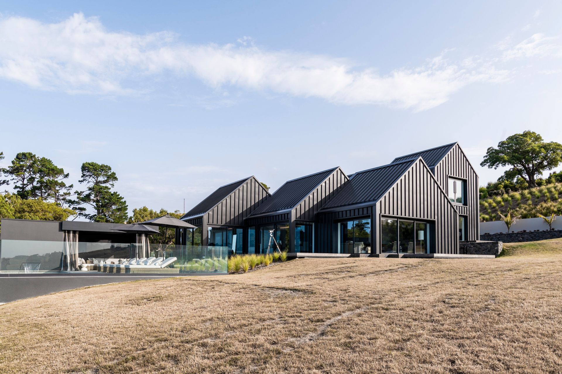 A single metal cladding material is used for the entire exterior cladding and roofing in a "flax pod" dark colour.