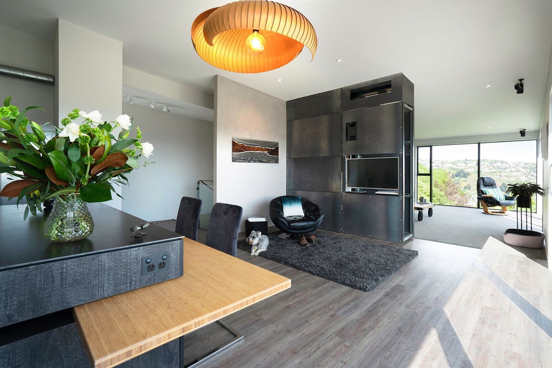 Dining and living area divided by a bespoke design by Peter Dunbar for a pivoting steel wall which includes a TV and air-conditioning unit.