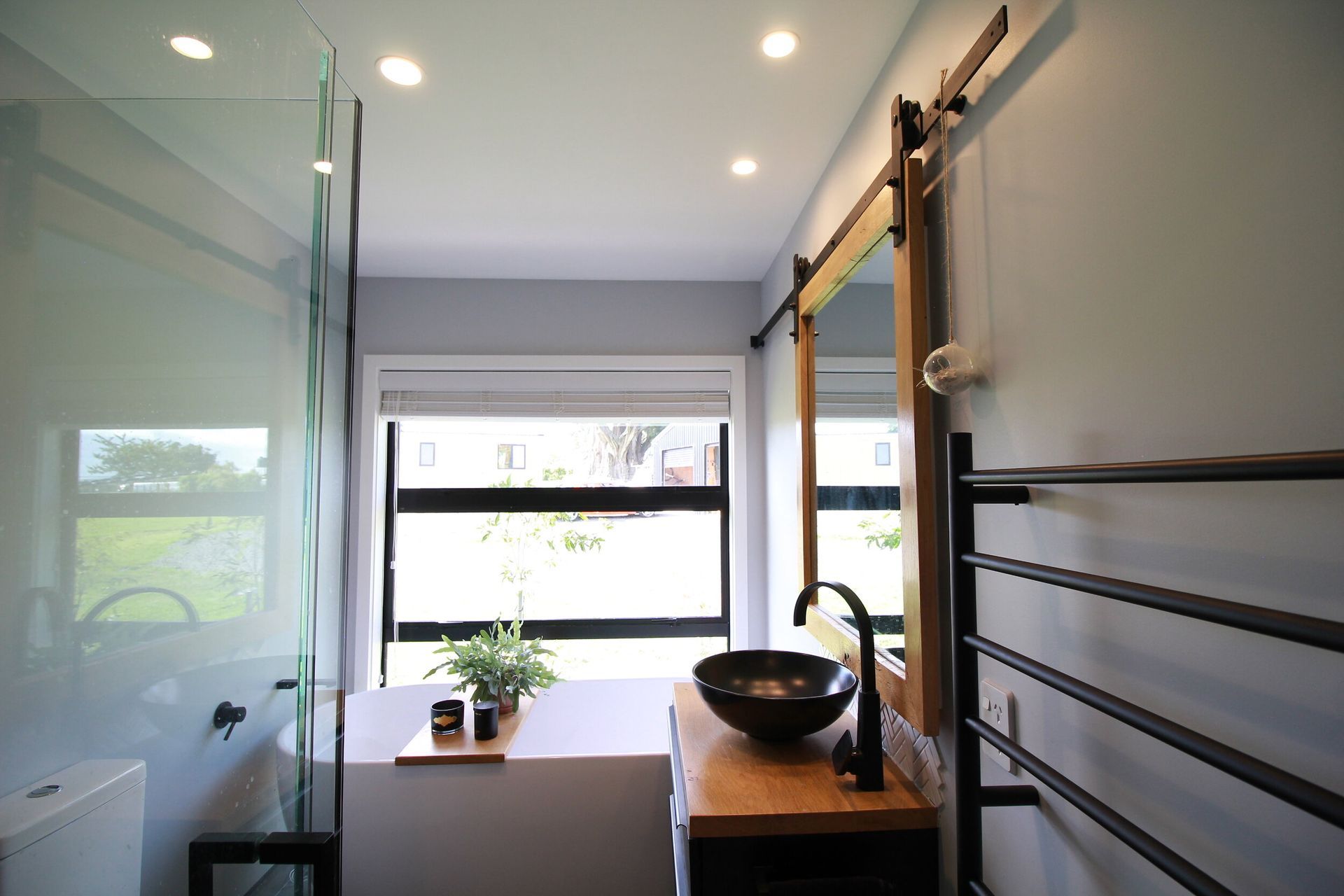 Snug but very usable bathroom. Has a 1800 bath at the far end, 1050x1050 tiled shower, 400mm free space either side of the dunny, and custom made recessed mirror cabinet with a barn slider mirror .