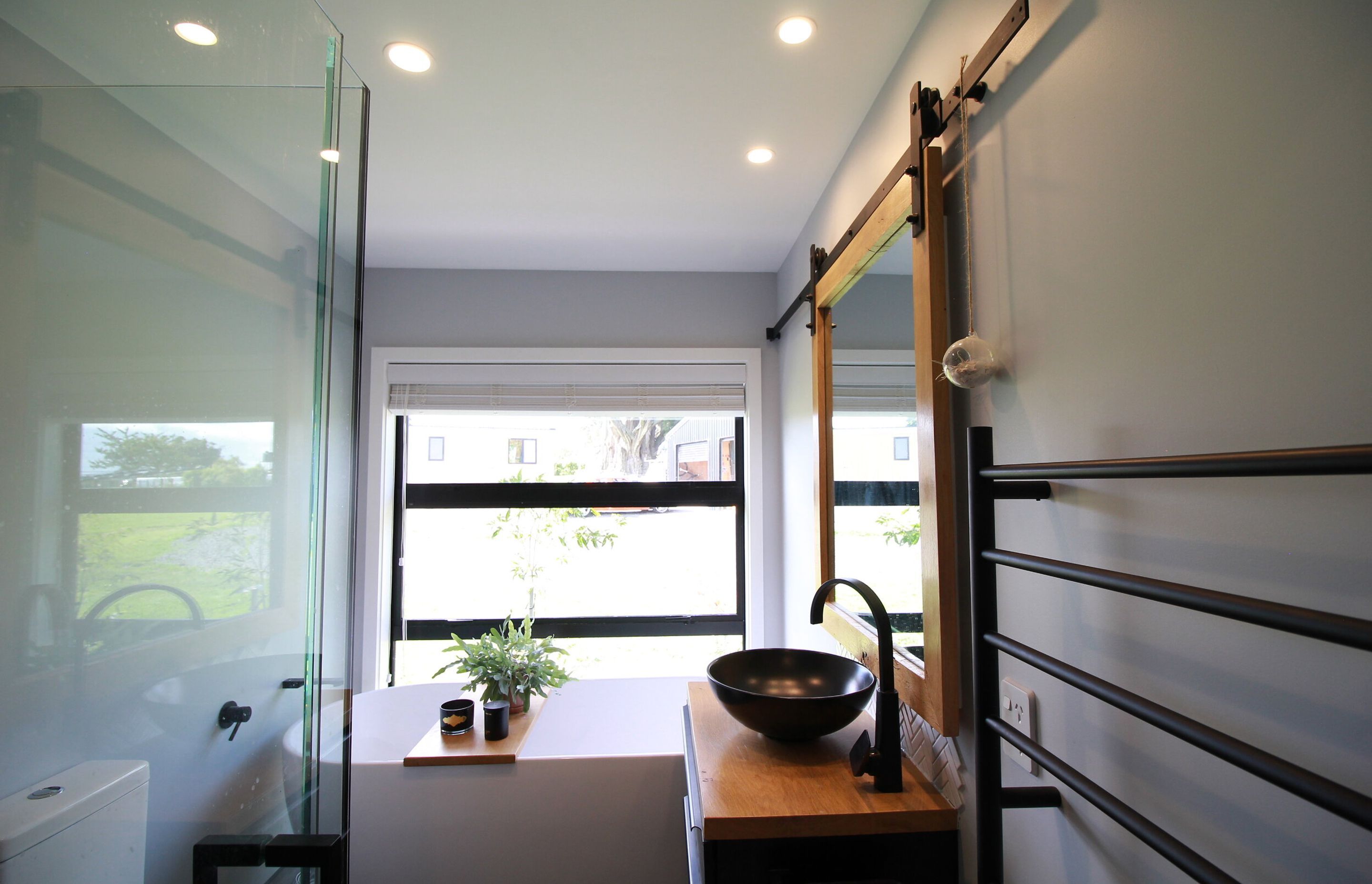 Snug but very usable bathroom. Has a 1800 bath at the far end, 1050x1050 tiled shower, 400mm free space either side of the dunny, and custom made recessed mirror cabinet with a barn slider mirror .