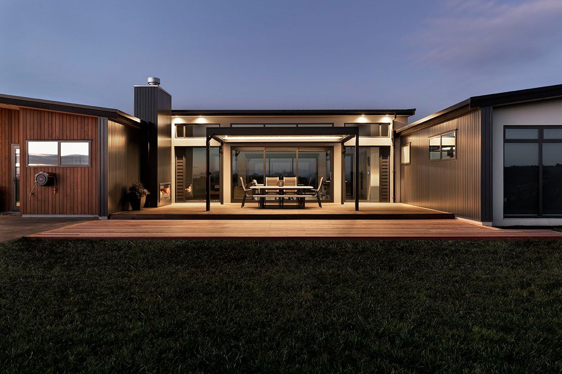 Rear outdoor living spaces have a warm light and ambience with the fireplace