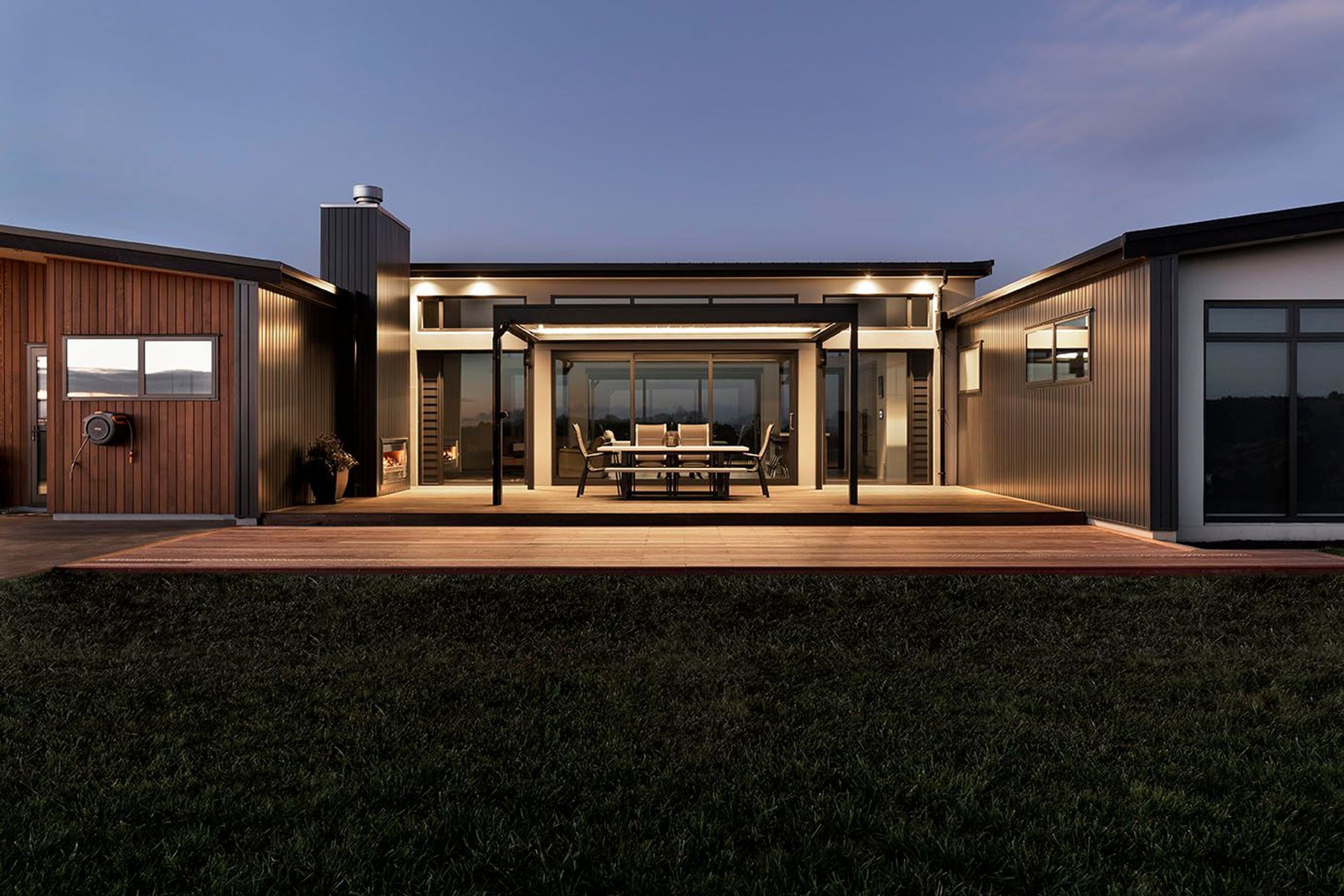 Rear outdoor living spaces have a warm light and ambience with the fireplace