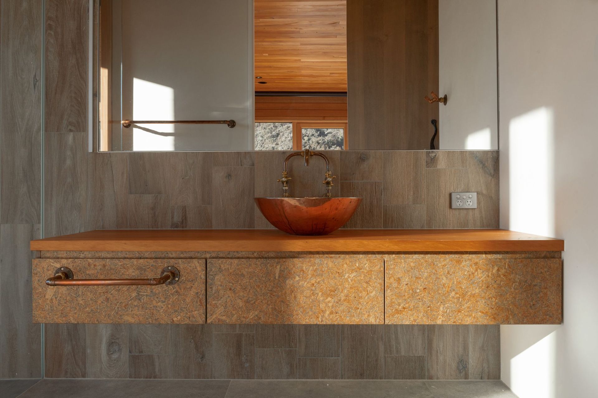 The ensuite features a custom strand board vanity and a handmade copper vessel basin.