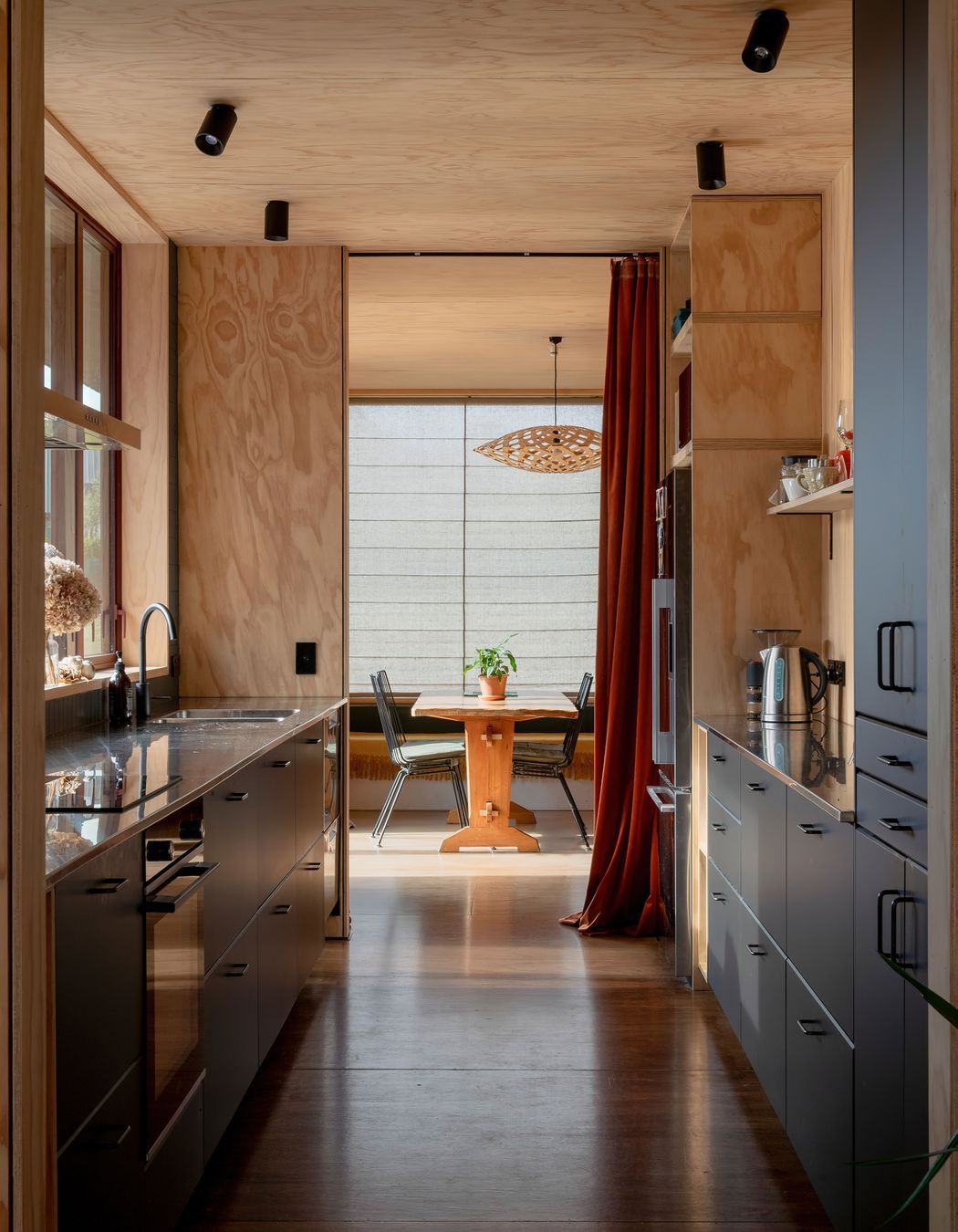 The galley-style kitchen with living areas at both ends. The pendant light is Flax by David Trubridge, and the flooring is Meranti plywood.