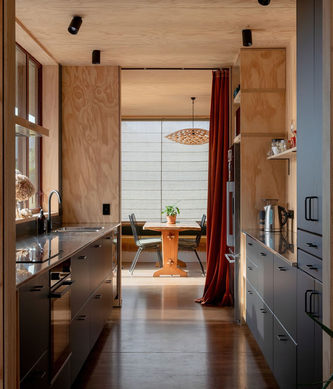 The galley-style kitchen with living areas at both ends. The pendant light is Flax by David Trubridge, and the flooring is Meranti plywood.