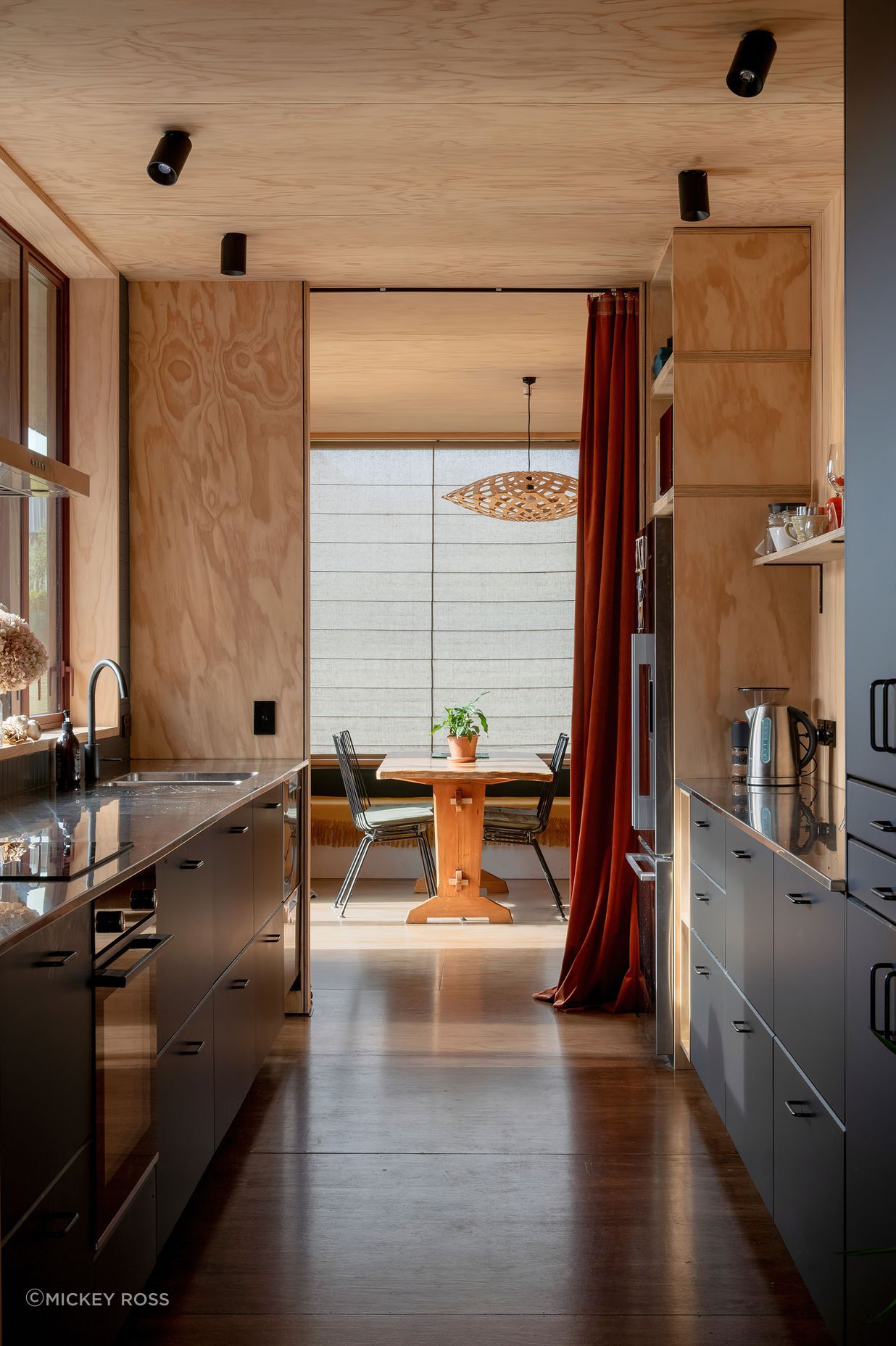 The galley-style kitchen with living areas at both ends. The pendant light is Flax by David Trubridge, and the flooring is Meranti plywood.