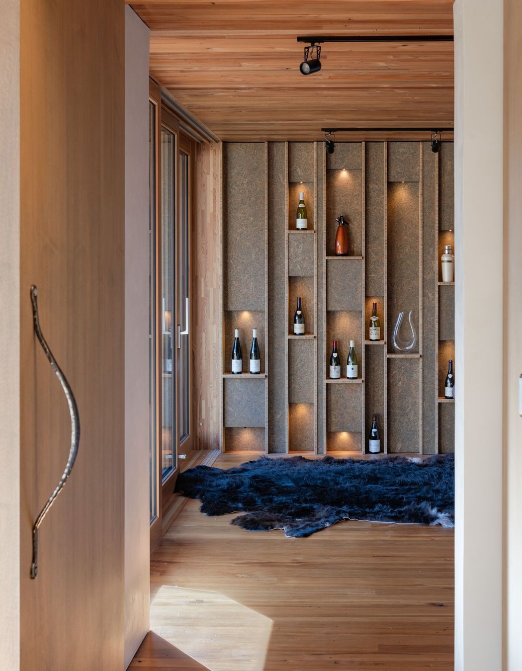 A custom feature wall in the second lounge displays some of the owner's—a wine maker—collection of wines.