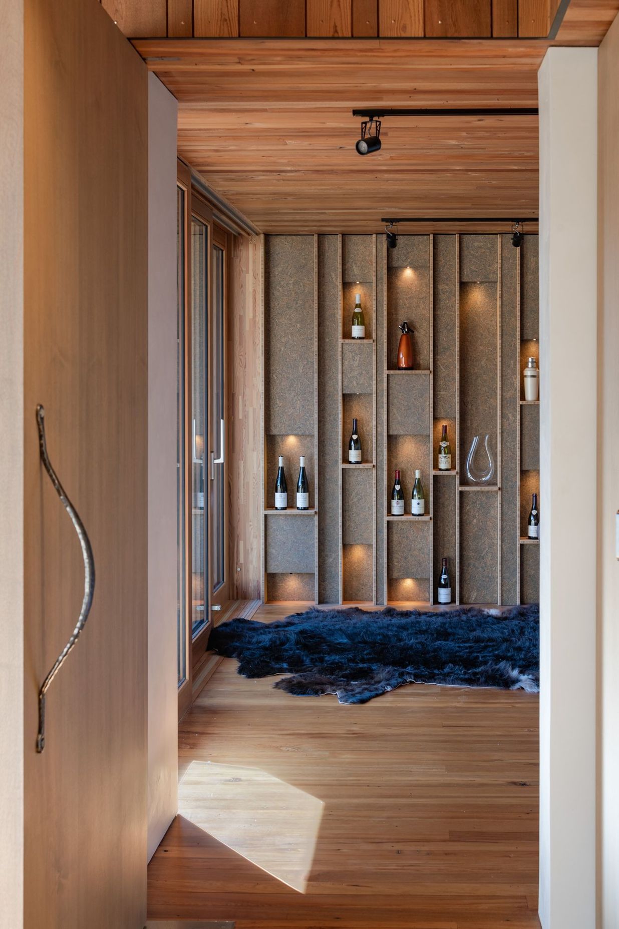 A custom feature wall in the second lounge displays some of the owner's—a wine maker—collection of wines.