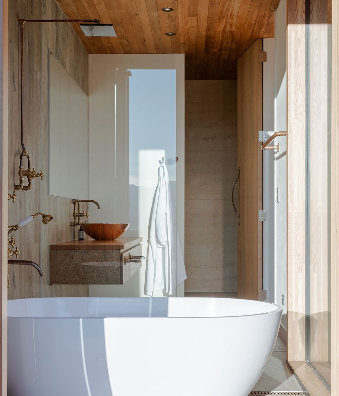 The free-standing bath sits within its own enclave with bifolding doors that open directly to the deck.