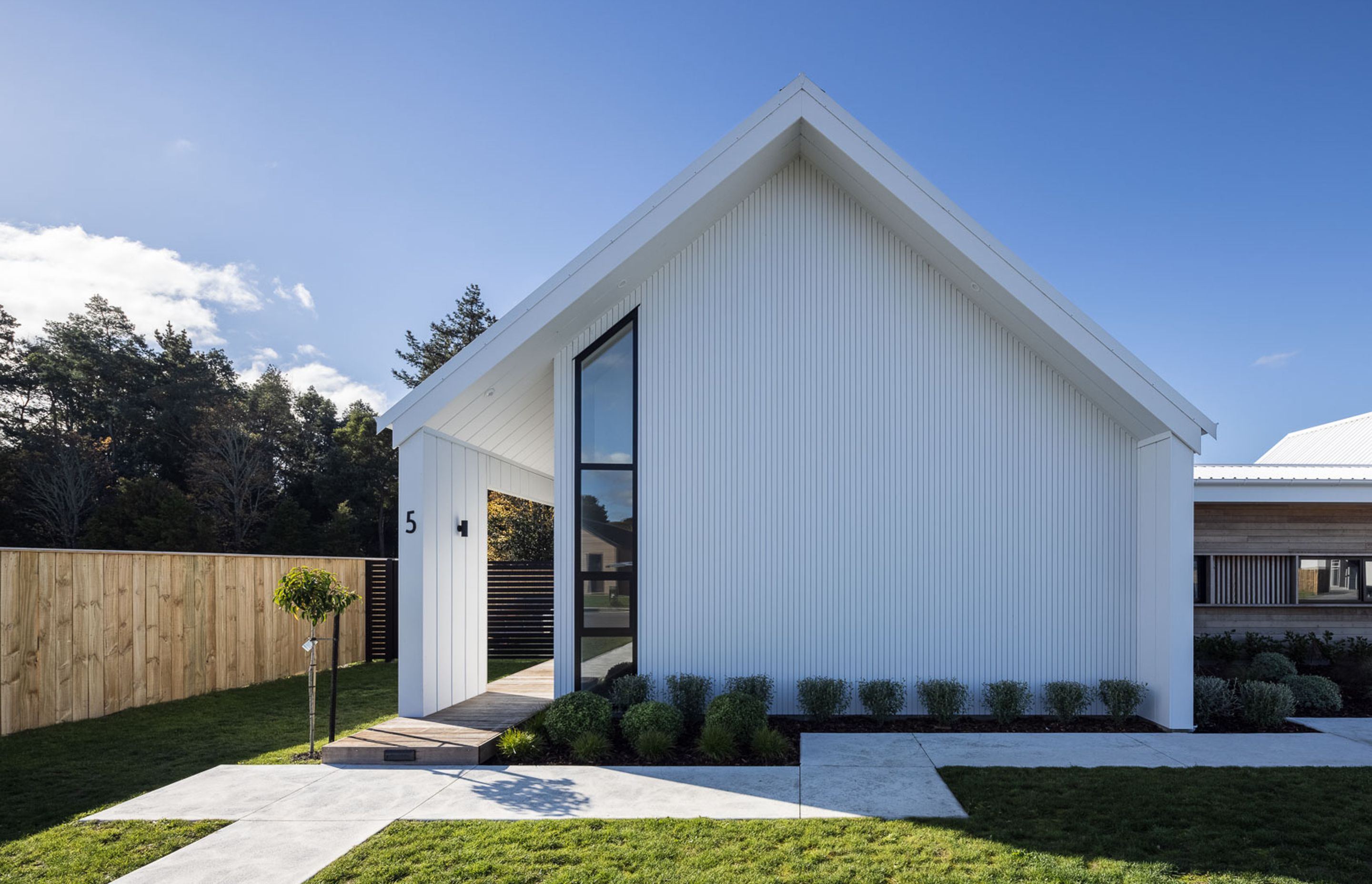 The eastern pavilion houses the living areas and features a set-back front door, again, maintaining the almost unbroken look of the gable end.