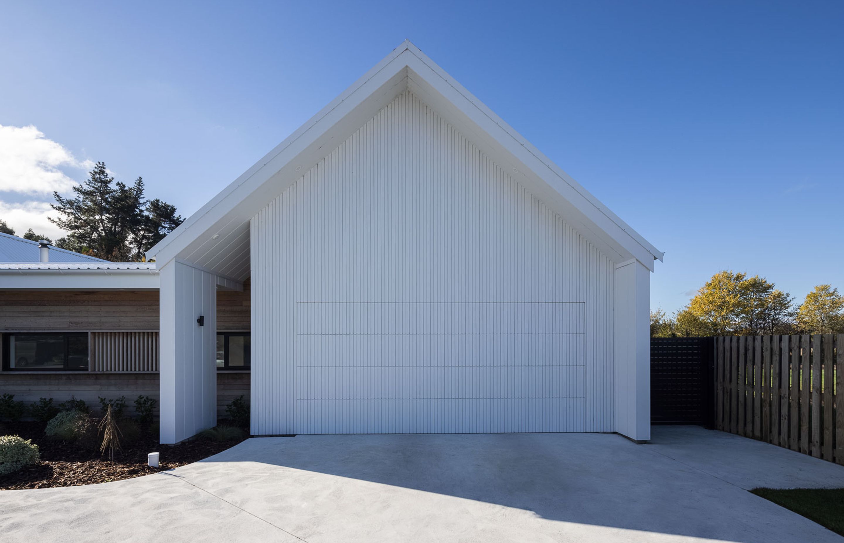 The flush-mounted garage door helps maintain the seamless look of the gable end on the eastern pavilion, which also houses the main bedroom.