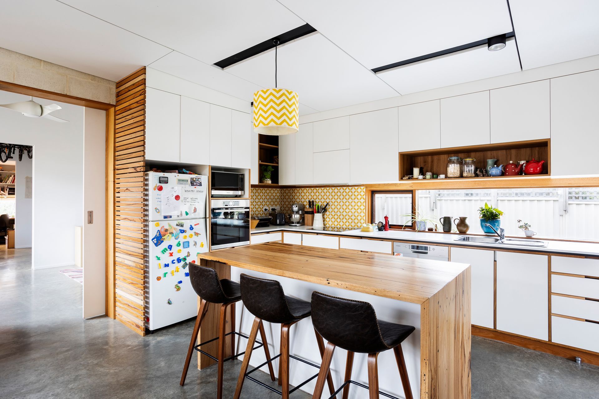 White and timber kitchen with recessed handles and fridge ventilation