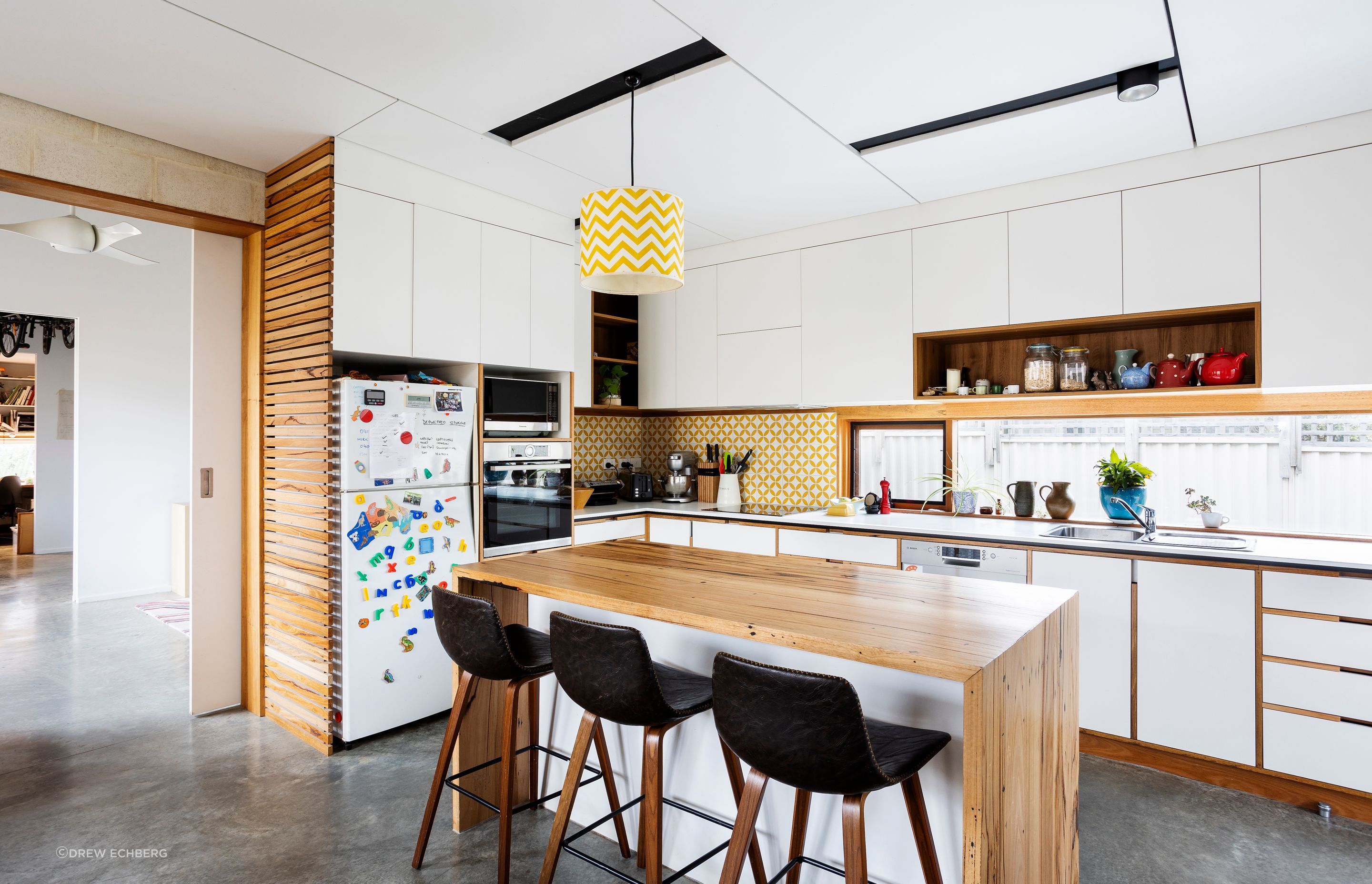 White and timber kitchen with recessed handles and fridge ventilation
