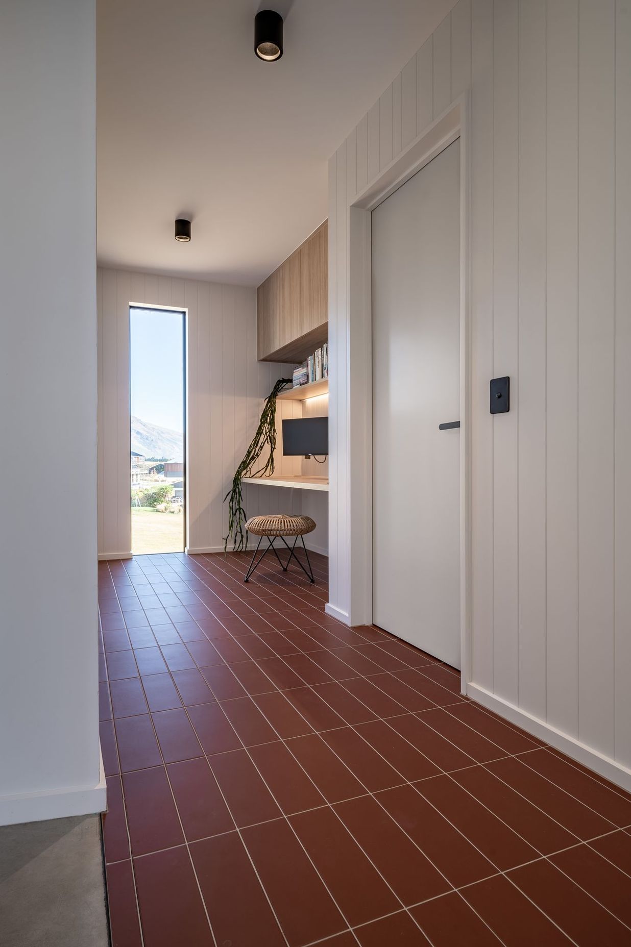 The entryway with terracotta tiles and built-in study for adults.