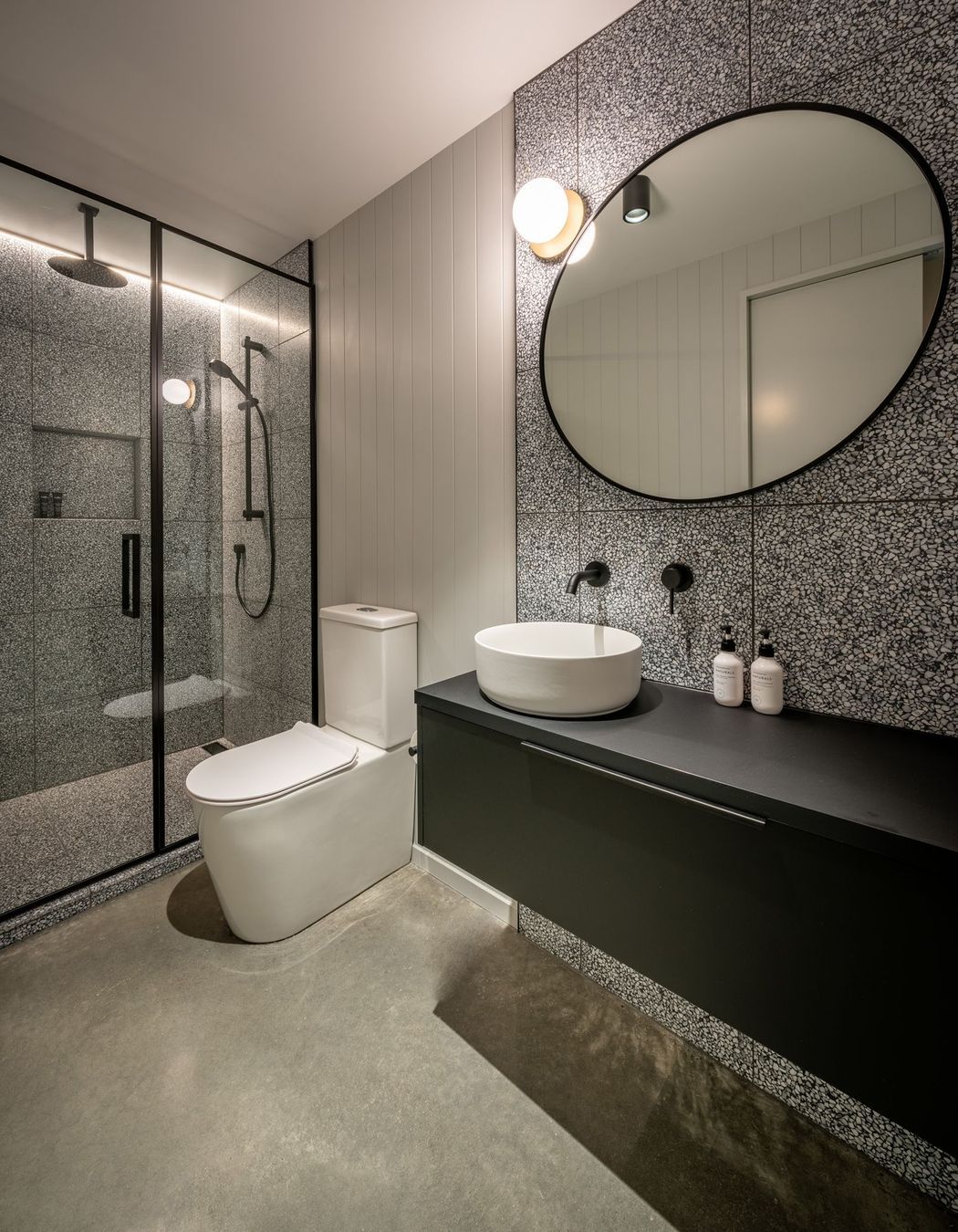 A third bathroom for guests features a concrete floor and black steel-framed shower.