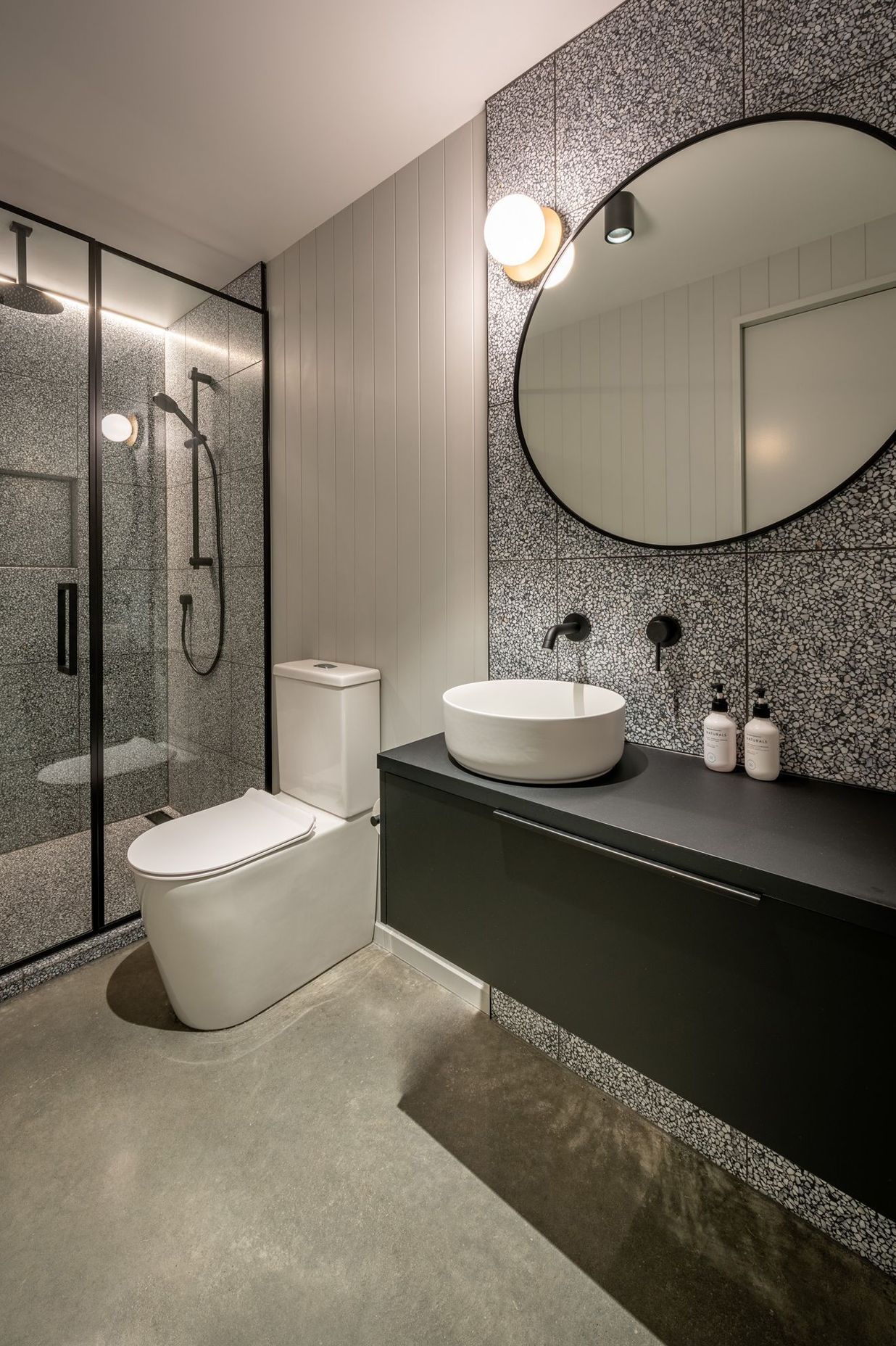 A third bathroom for guests features a concrete floor and black steel-framed shower.
