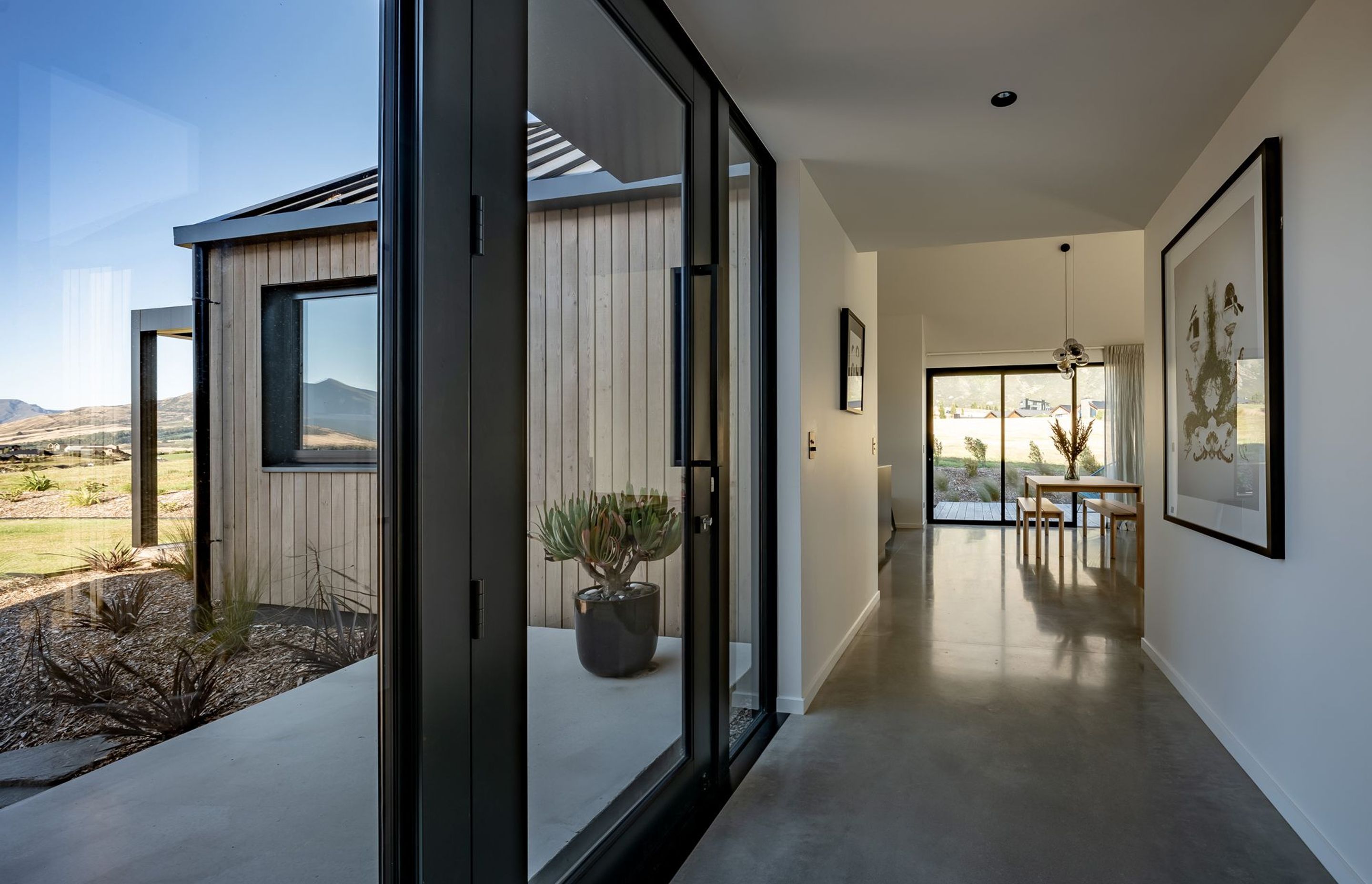 The glazed hallway to the living space provides a gallery wall for the homeowner's art collection on one side.