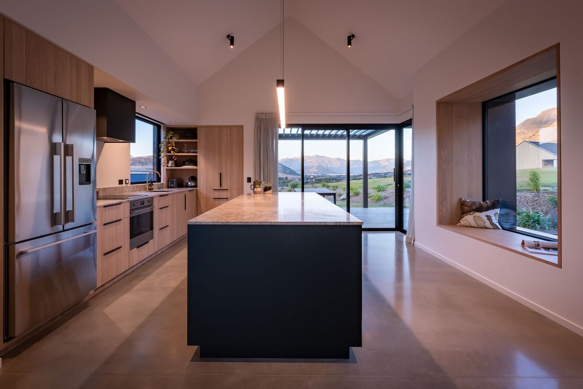 The kitchen materiality brings the outdoors in through timber cabinetry and a stone benchtop.