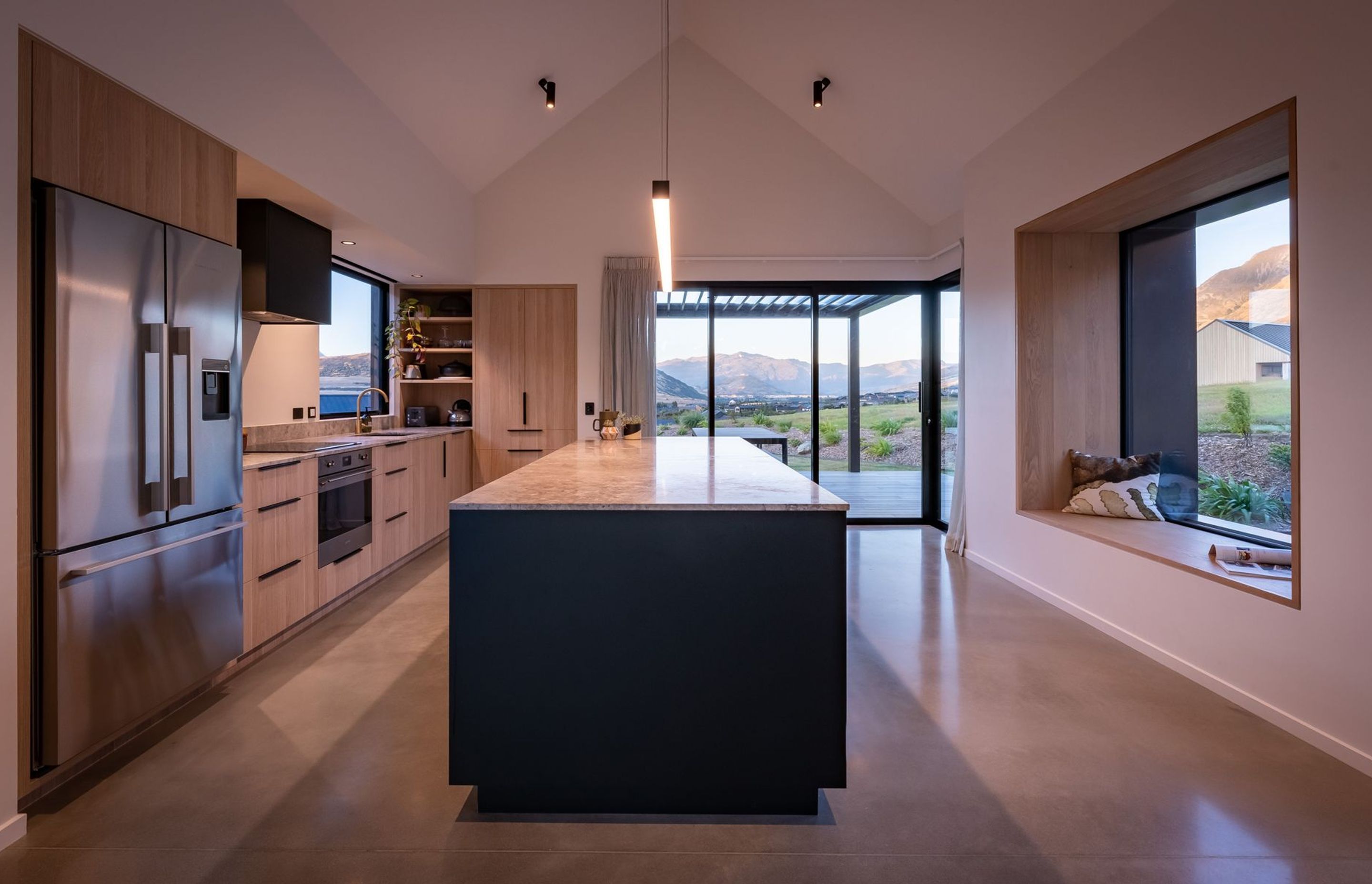 The kitchen materiality brings the outdoors in through timber cabinetry and a stone benchtop.