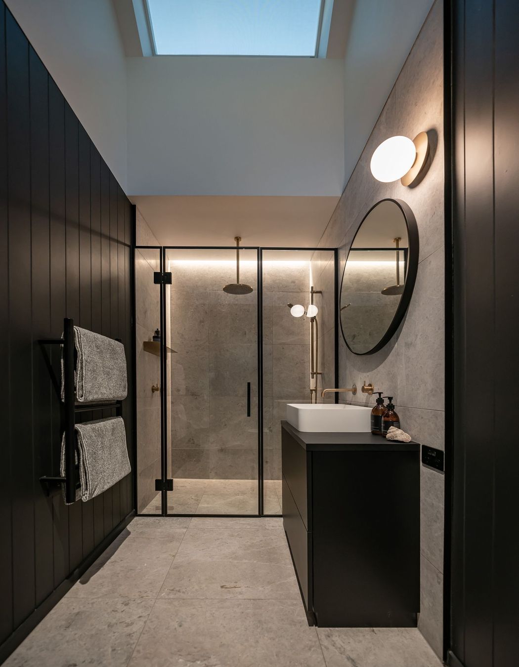 The master bathroom creates a mood through dark colours and luxury tiling.