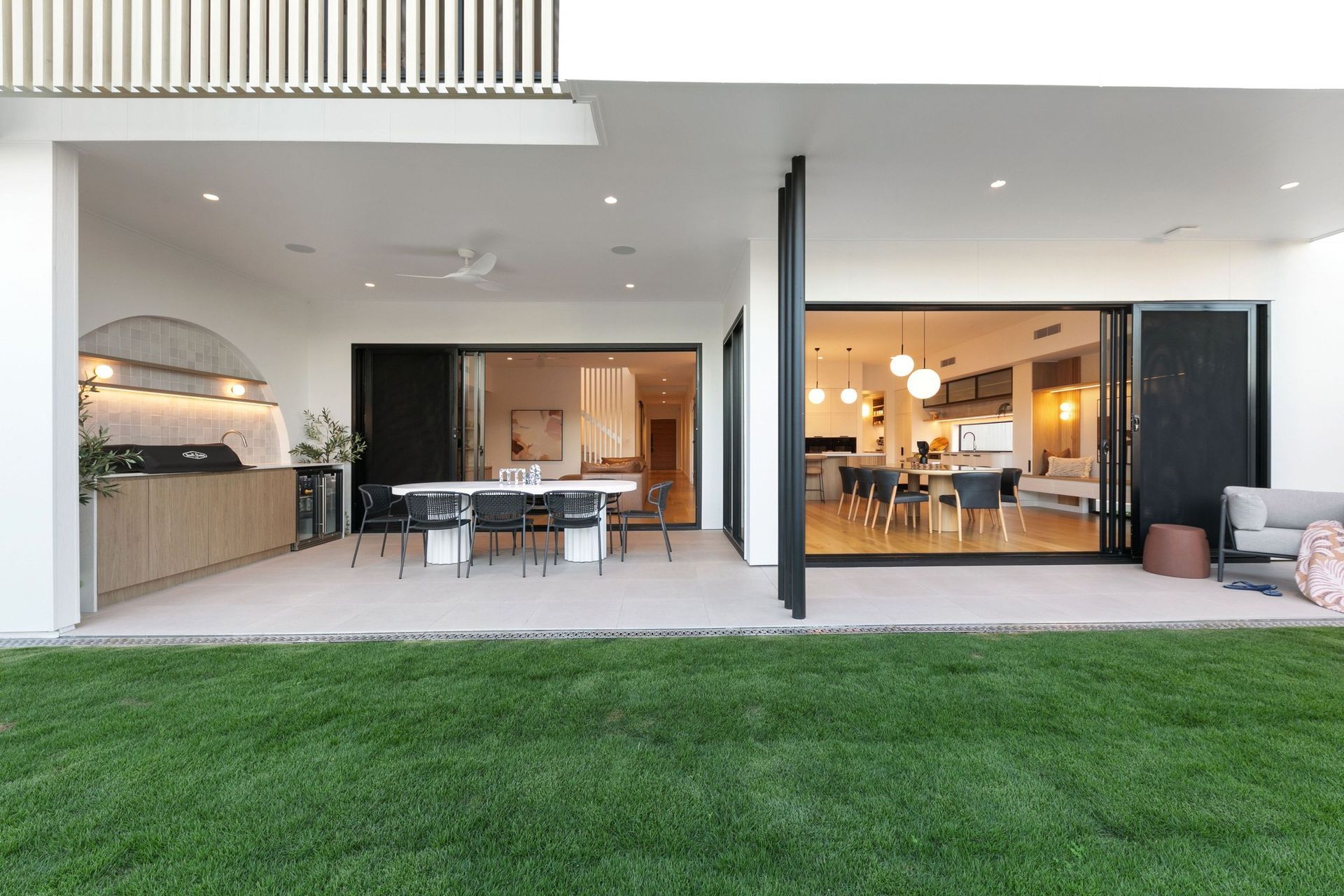 The whole rear of the home opens to the lawn — alfresco, dining and kitchen in one line.