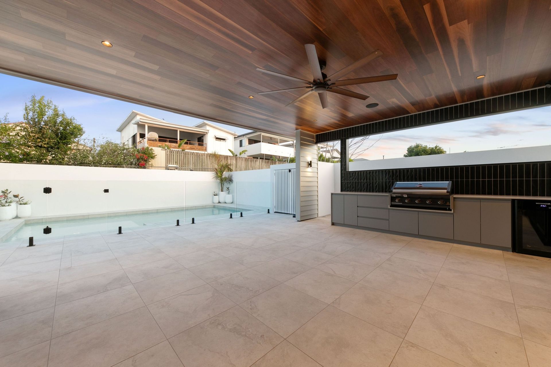 The alfresco works year-round — barbecue, fridge and shade beside the water.