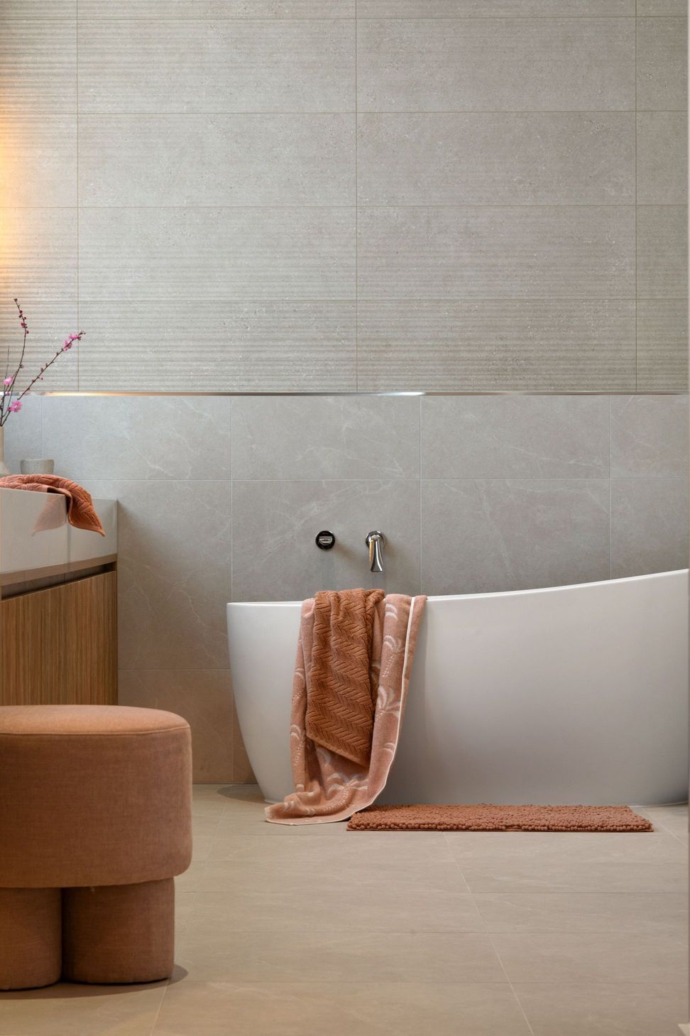 Stone in two textures wraps the bathroom, with a curved bath at its centre.