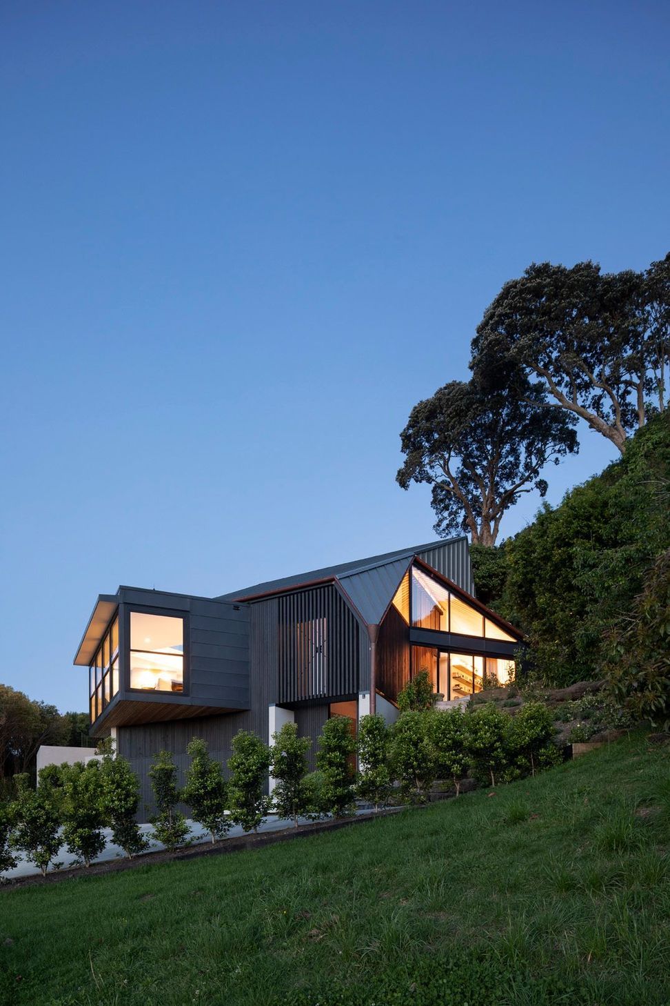 Situated at the end of a 500m driveway, which winds around 12 other houses, the home is perched on the slope of a volcanic crater with views over a wooded dell to the north and Auckland city to the west.
