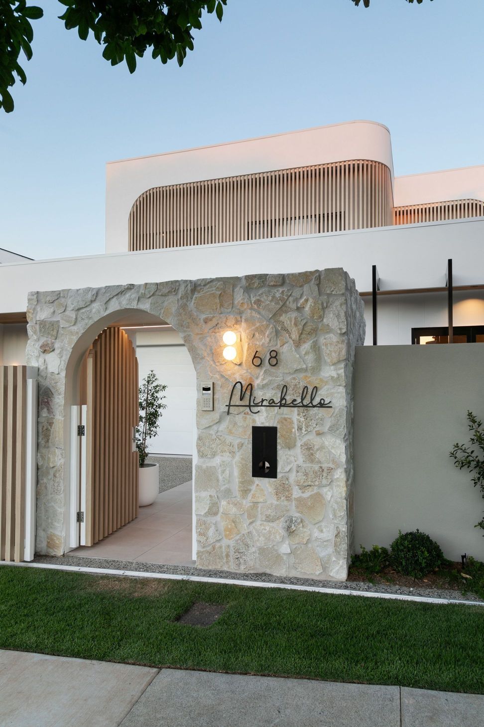 A rough stone arch marks the entry, framing the timber gate and the curved screen above.