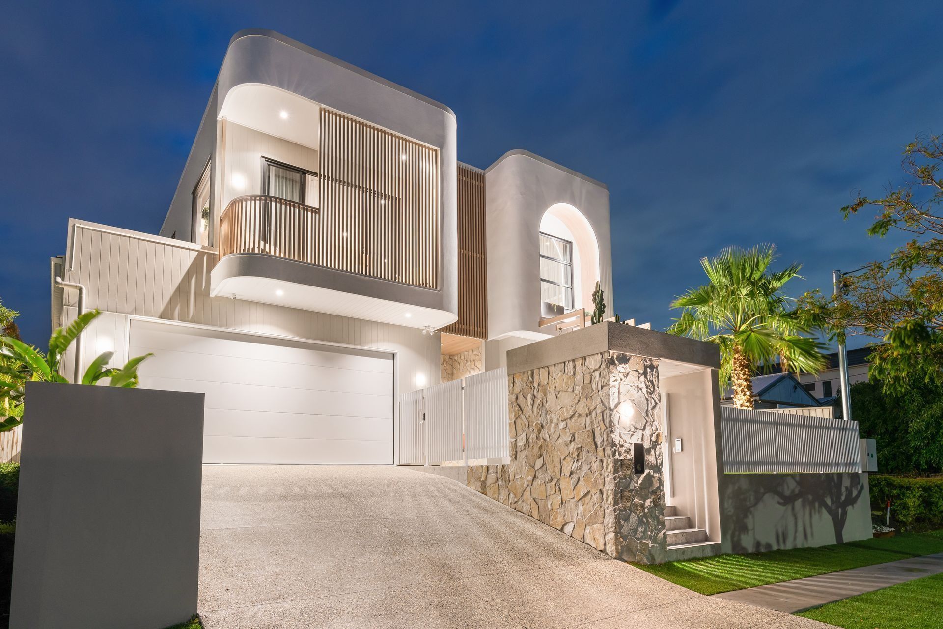The curved white facade and timber screening give the home its quiet, confident street presence.