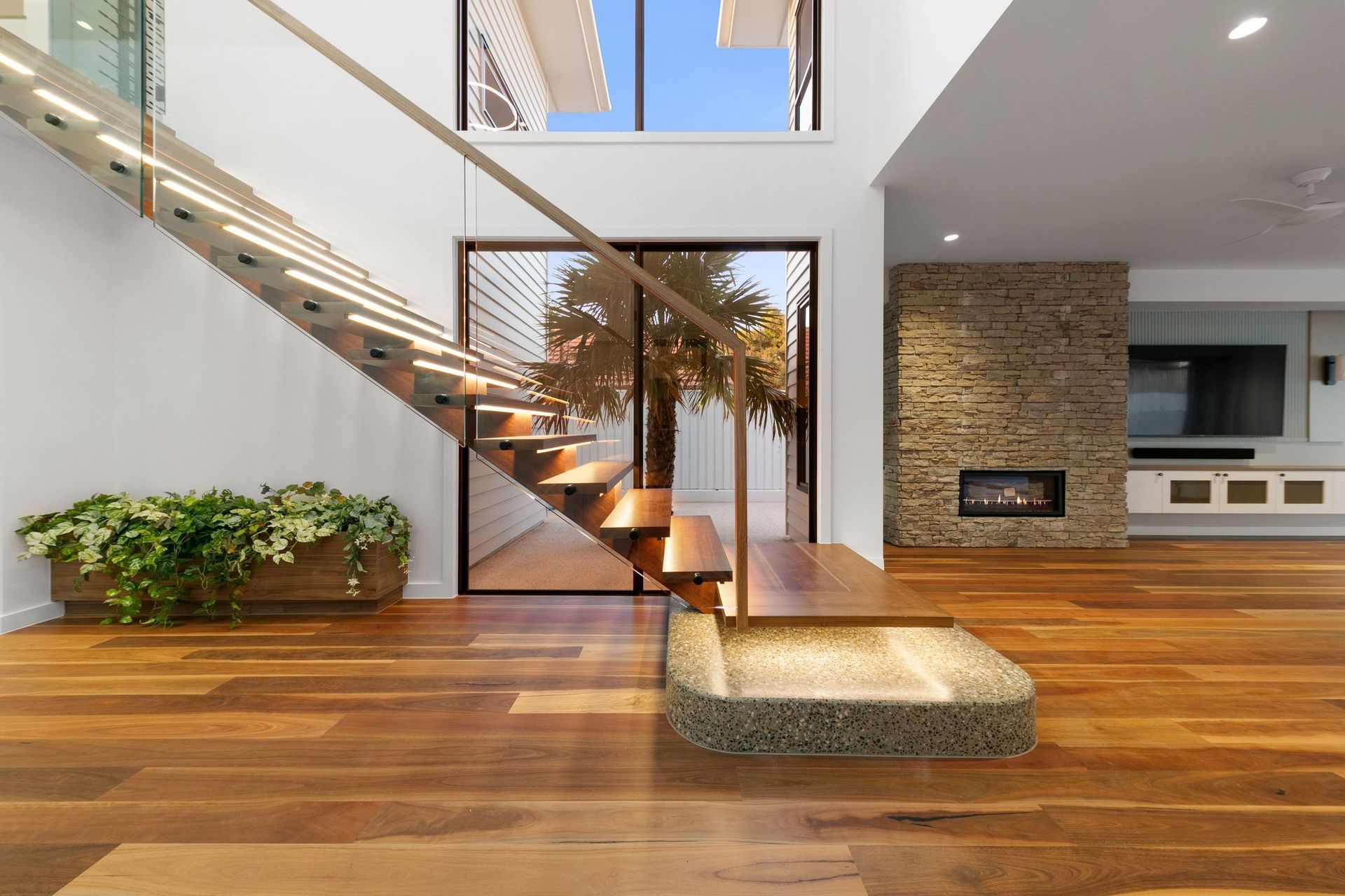 The stair lands on a curved terrazzo plinth — a small moment of craft beside the stone fireplace.