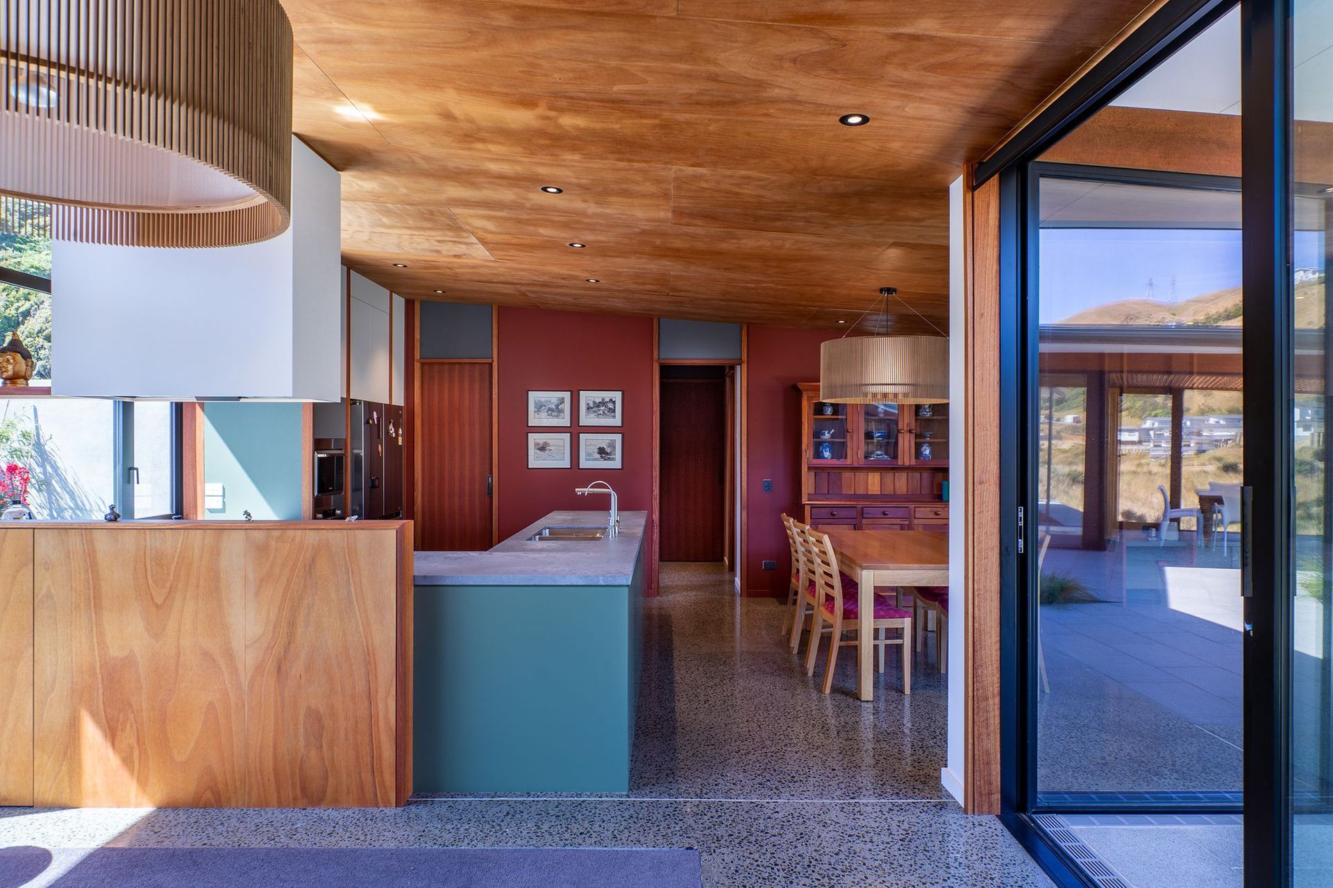 The owners wanted a palette of natural timbers and red-brown colours to complement their collection of Asian art. The rich tones of okoume ply and deep red have been offset with some soft, natural greens and exposed concrete floors.