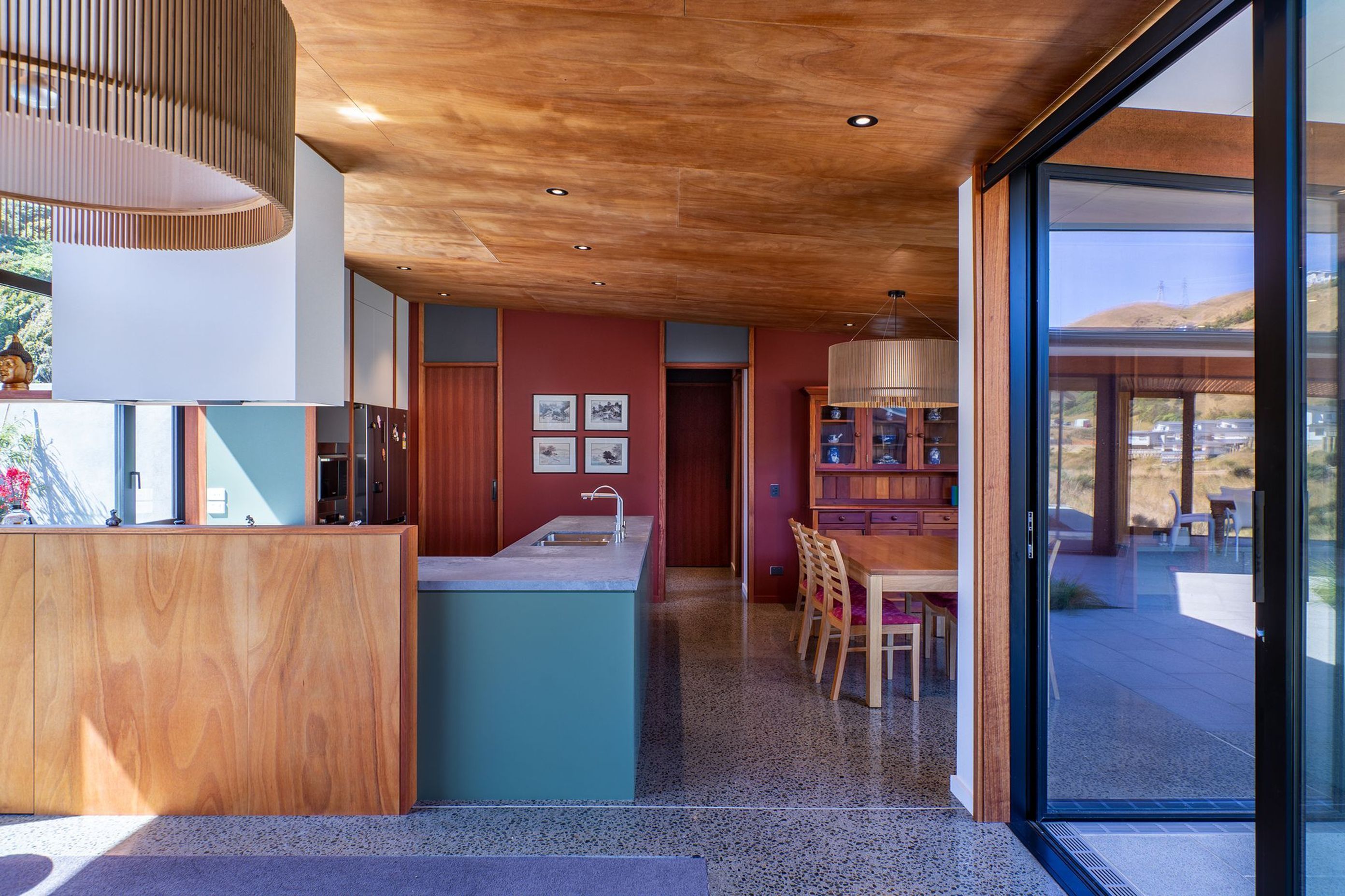 The owners wanted a palette of natural timbers and red-brown colours to complement their collection of Asian art. The rich tones of okoume ply and deep red have been offset with some soft, natural greens and exposed concrete floors.