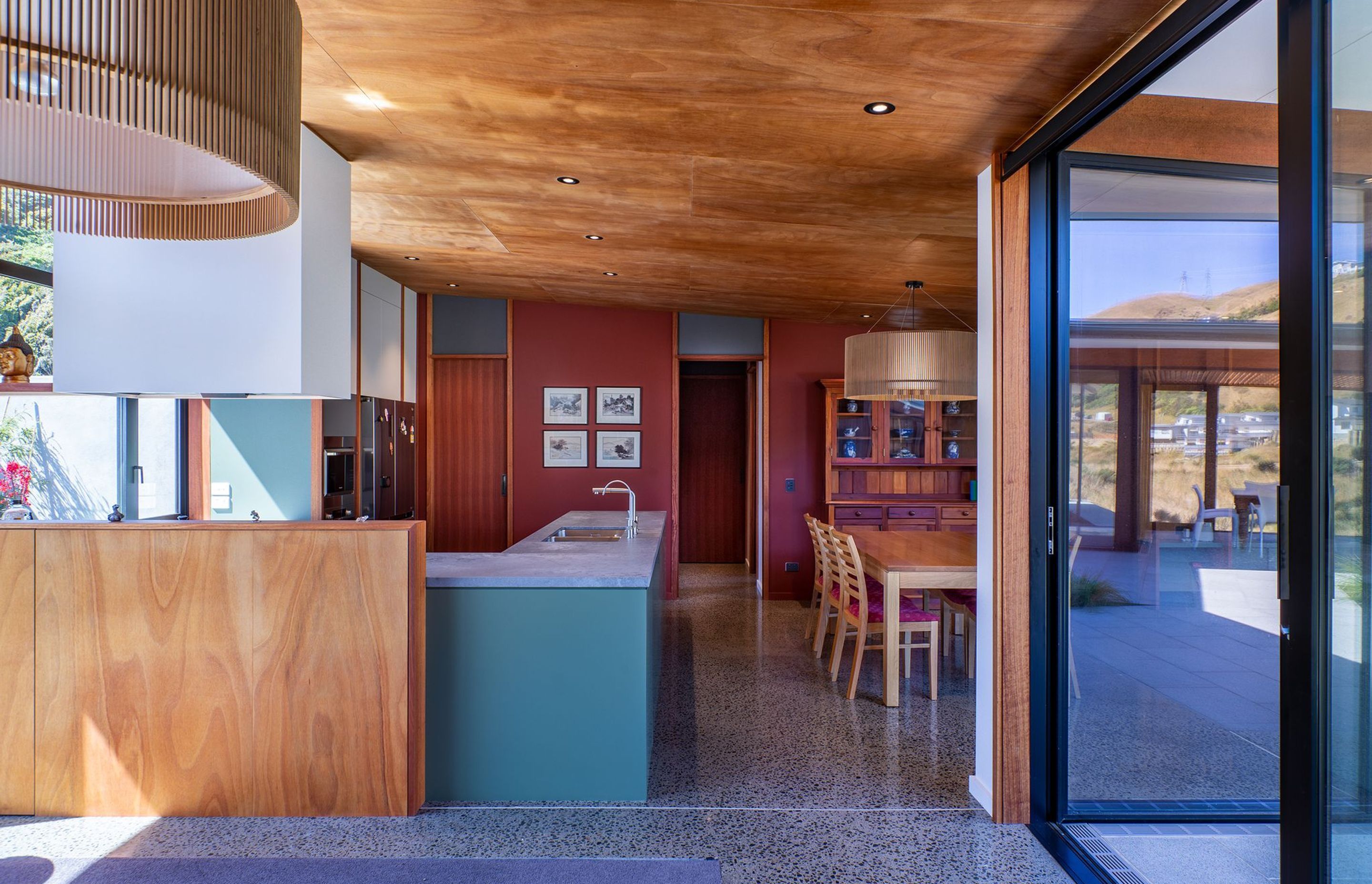 The owners wanted a palette of natural timbers and red-brown colours to complement their collection of Asian art. The rich tones of okoume ply and deep red have been offset with some soft, natural greens and exposed concrete floors.