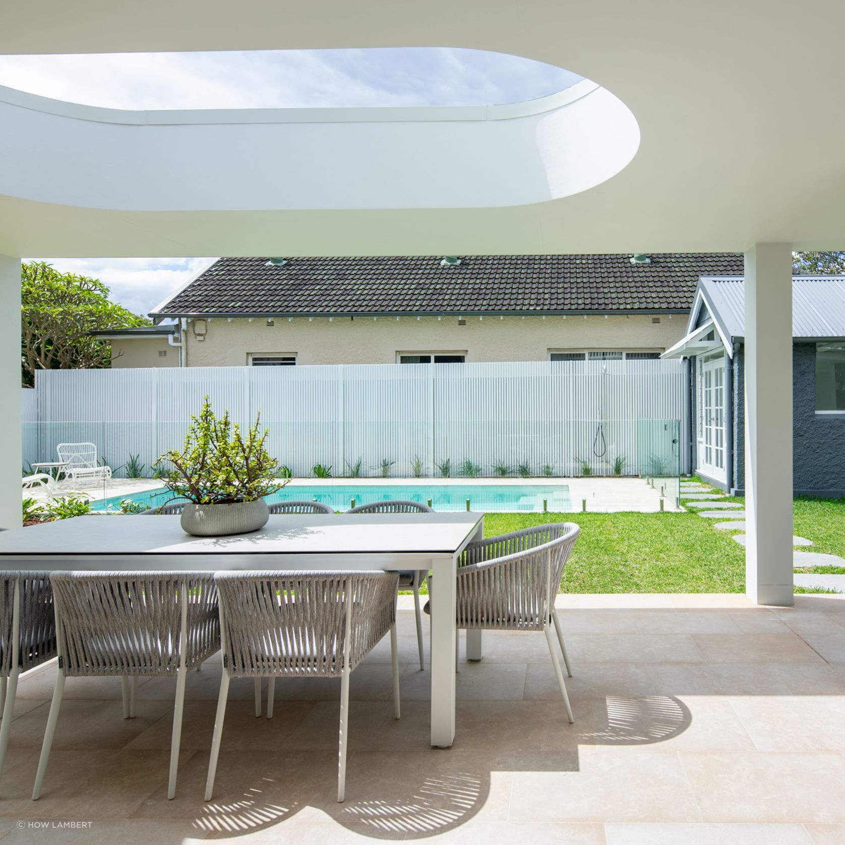 Lavarosa limestone alfresco terrace with circular skylight, outdoor dining area, and pool view