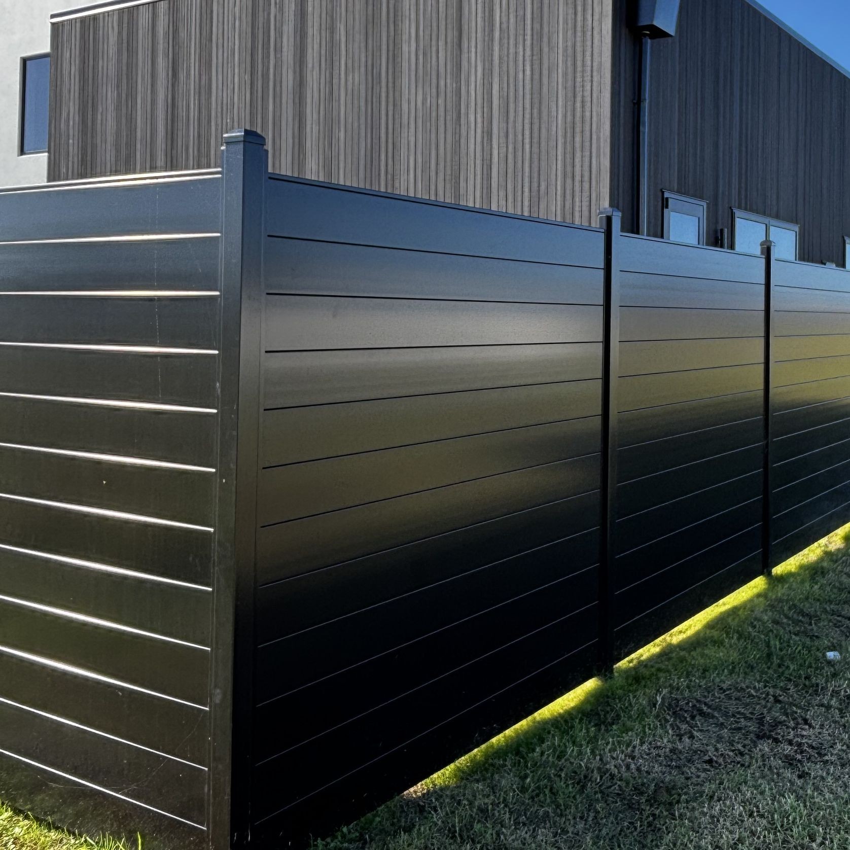 Black Horizontal Slat Solid boundary fence around architectural resdiential home with mountain in background