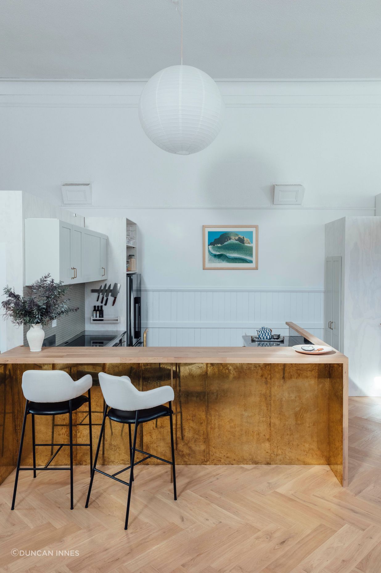 The kitchen features a timber breakfast bar and brass details. 