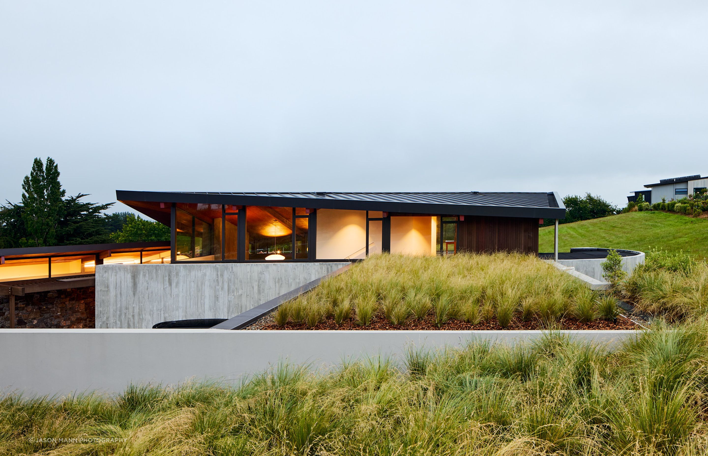 A three-car, half-buried garage is embedded into the hillside and topped with tussock. 
