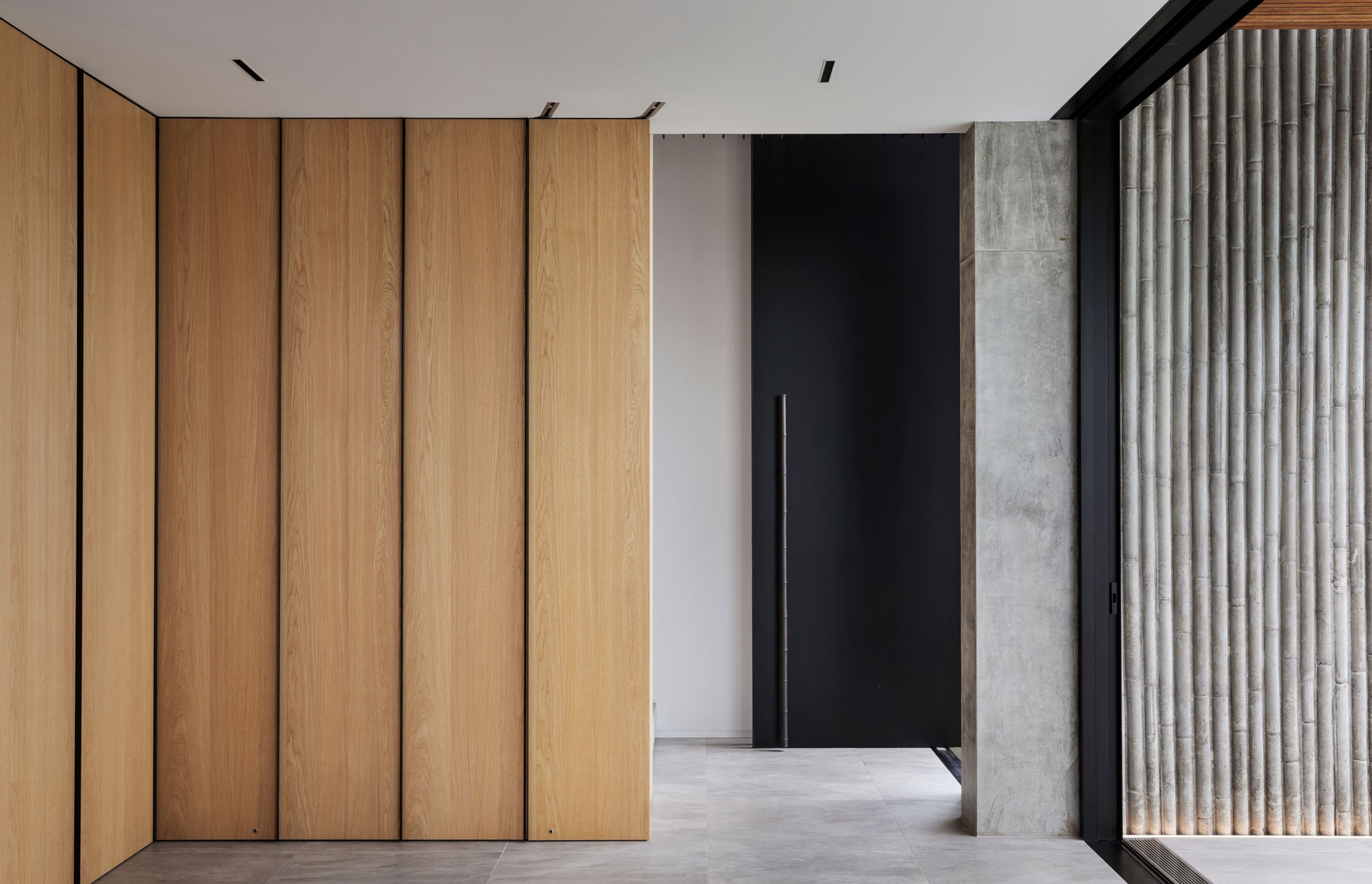 Sliding doors open up to reveal a full bar set-upm, while the front door features a metal bamboo handle, complementing the bamboo-shuttered in-situ concrete wall.