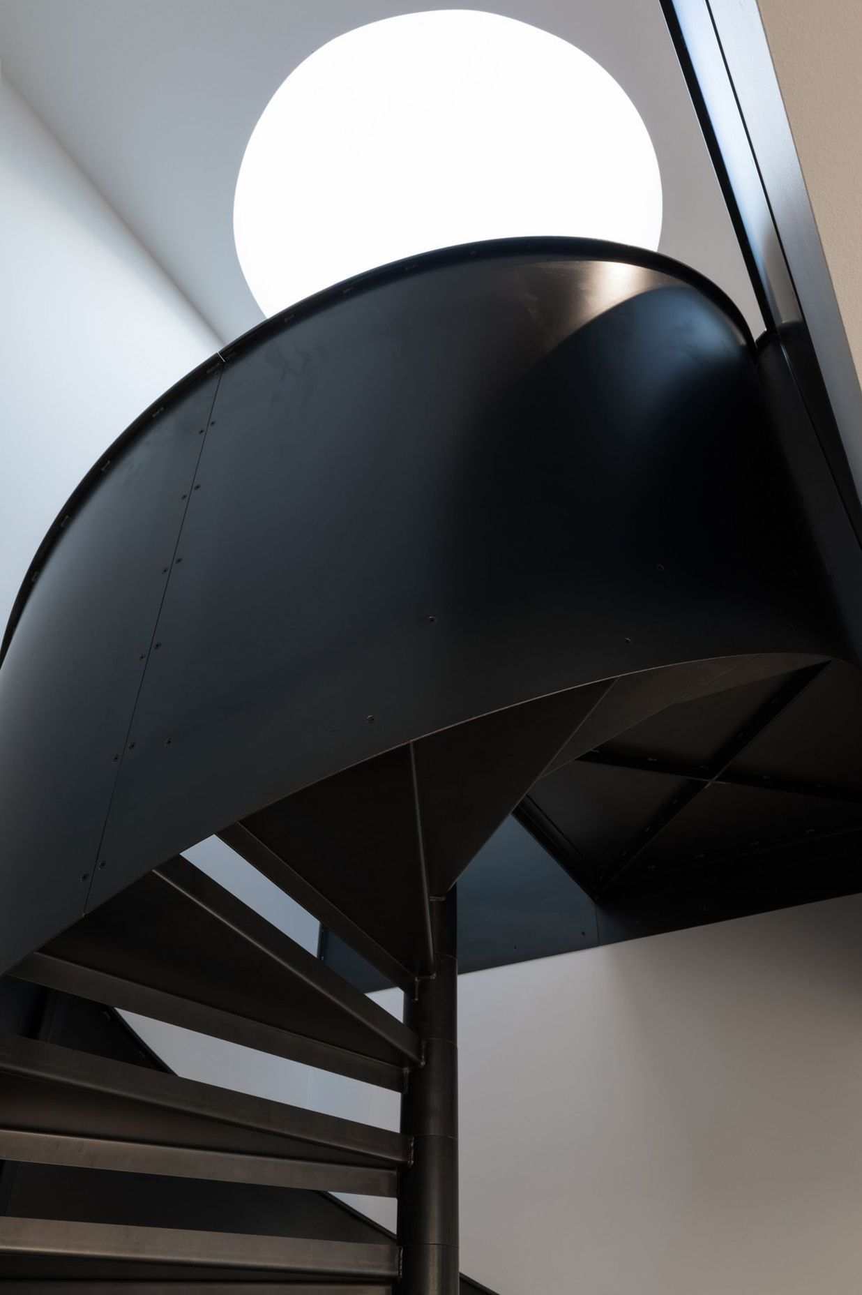 A black spiral staircase made in steel plate is a key architectural feature.
