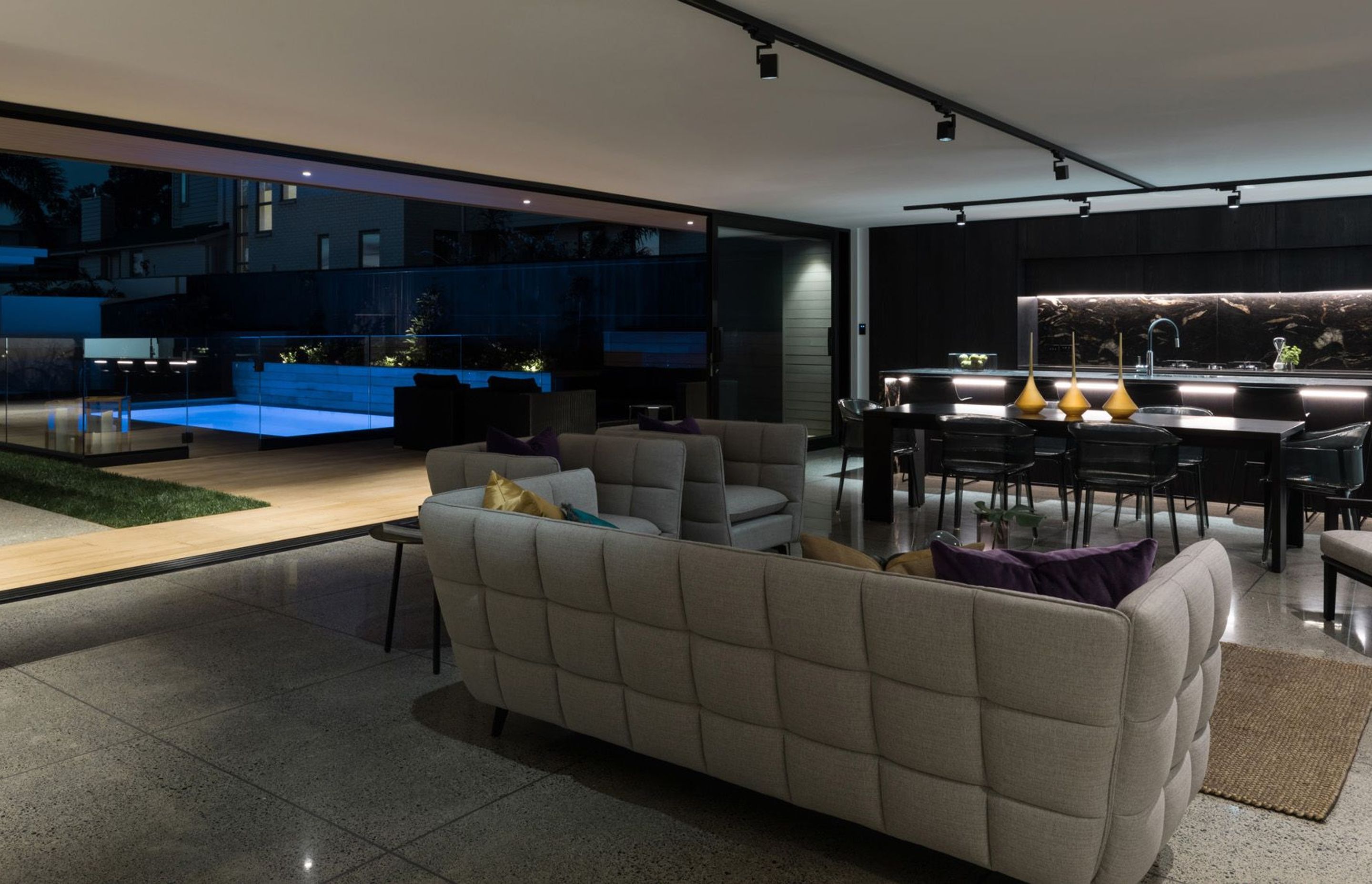 A large kitchen and living area is perfect for entertaining, with the added attraction of a swimming pool lit up like a light feature.