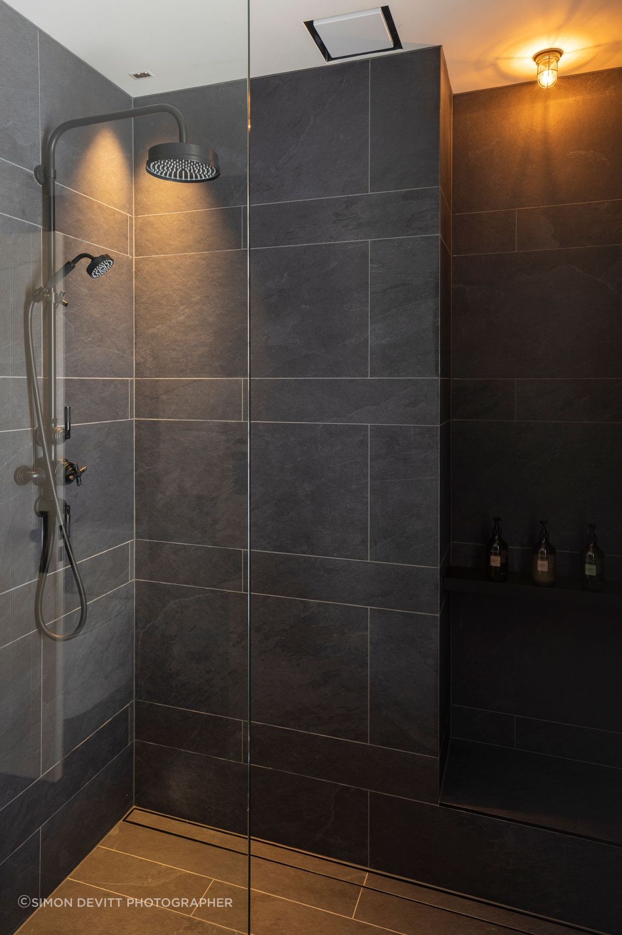 Black textured tile in the bathrooms contrasts with white board and batten that is used in the hallways.