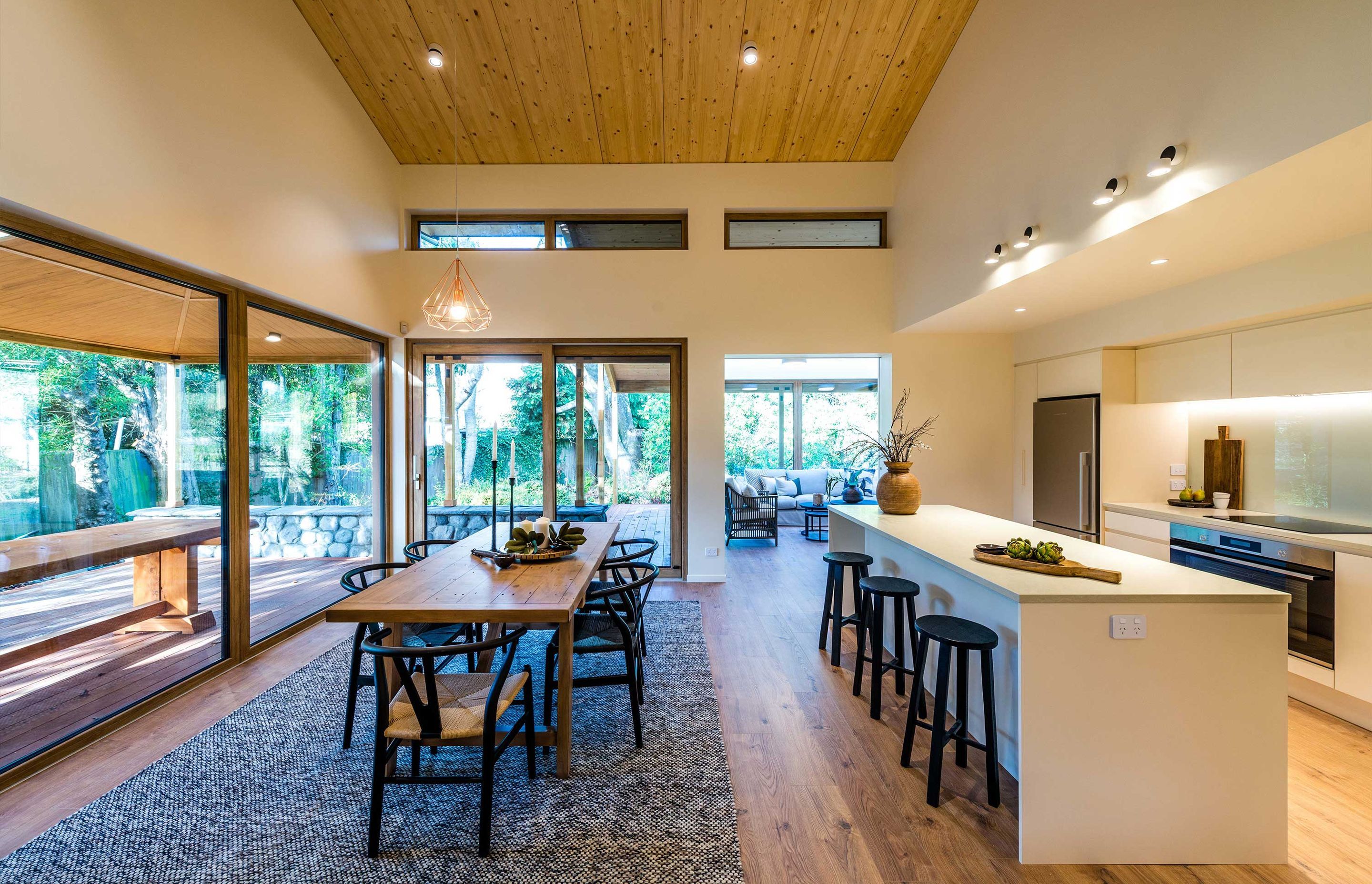 Kitchen dining looking towards sunroom. The ceiling is structural solid timber panels that have a warm roof on top.