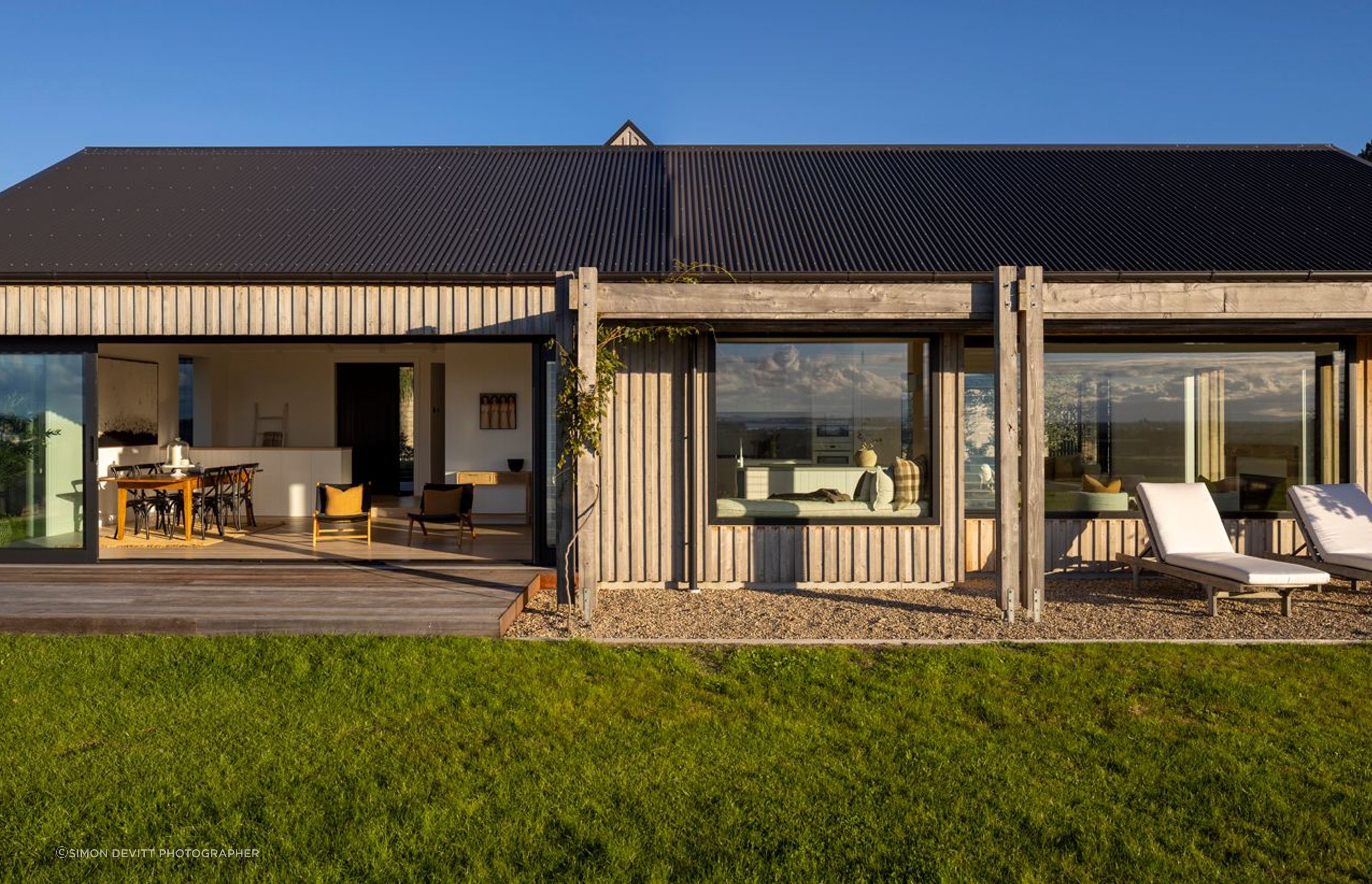 A view of the living spaces from the front lawn; the board and batten cladding is in cypress hardwood, which has a rustic yet refined aesthetic.
